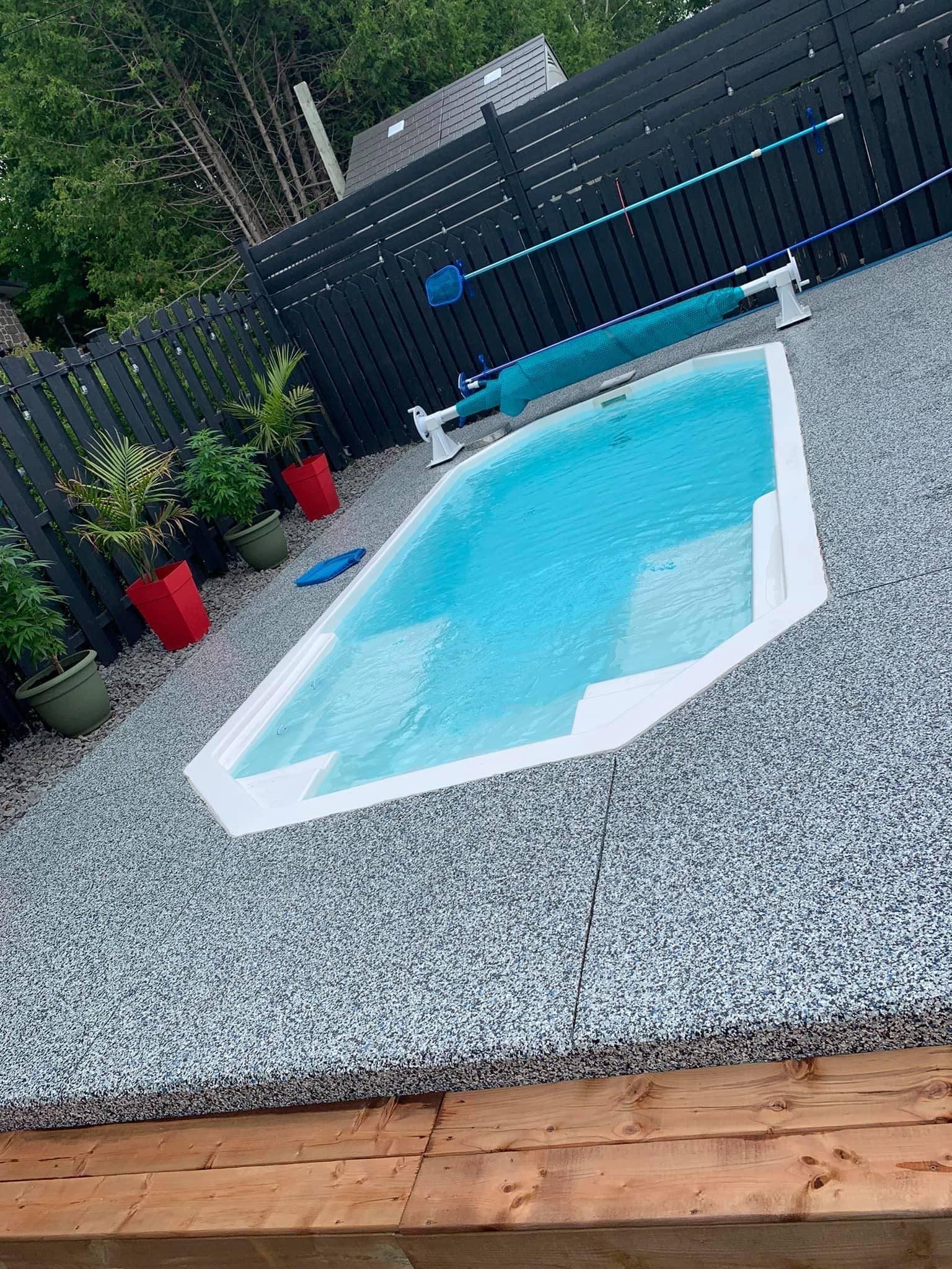 Une petite piscine se trouve dans une cour à côté d'une clôture.