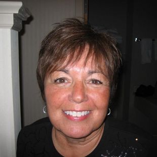 A woman wearing a black shirt and earrings smiles for the camera