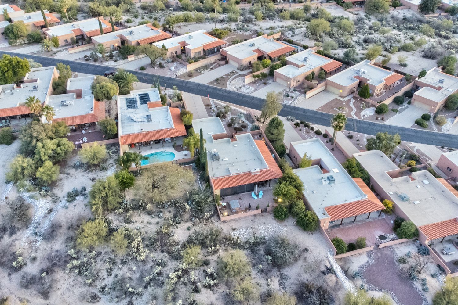 Aerial view of houses with flat roofs and a street winding through a desert landscape.