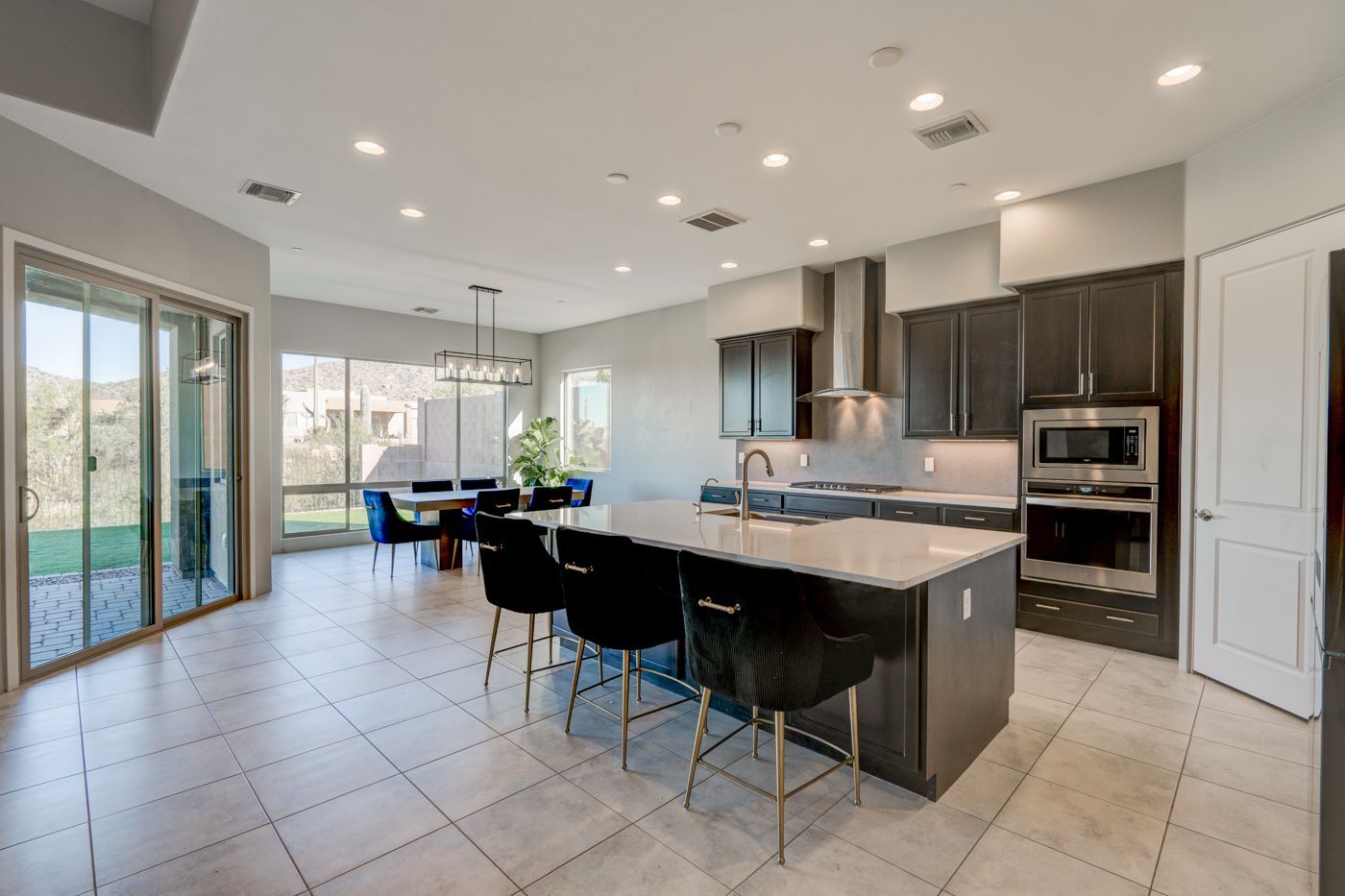 Modern kitchen with island and breakfast bar, dark cabinets, and dining area.