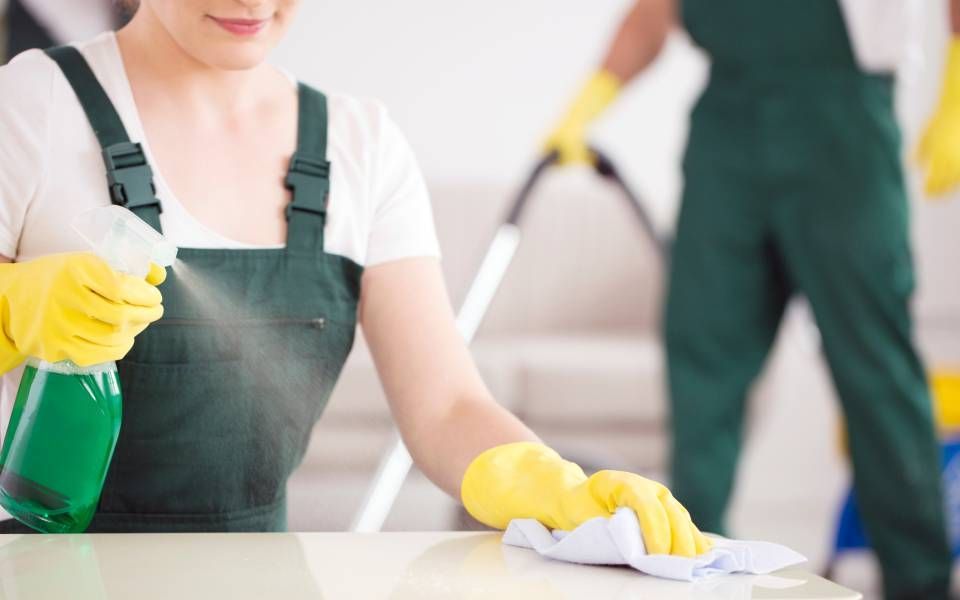 a lady cleaning the table with a spray bottle