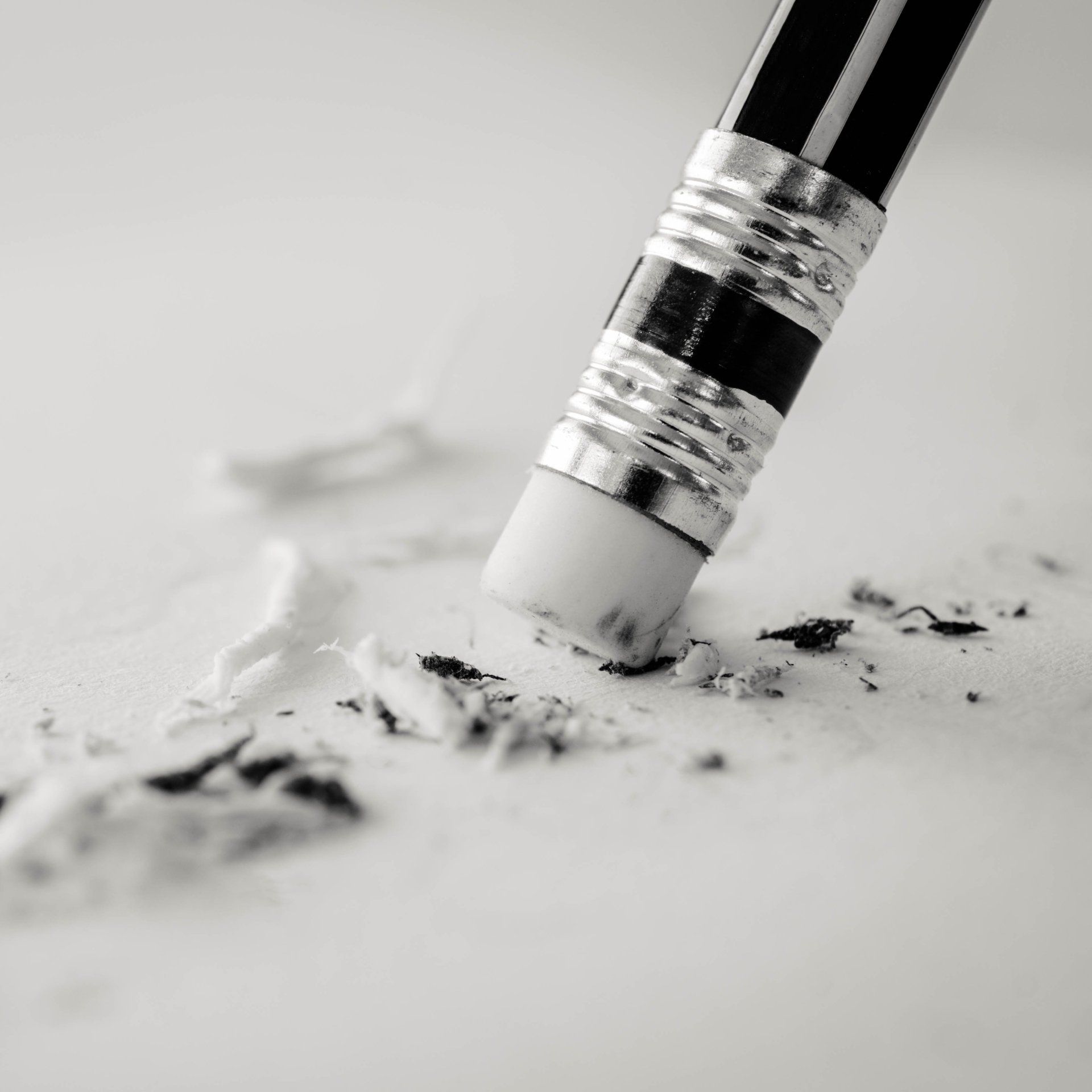 A black and white photo of a pencil erasing a piece of paper