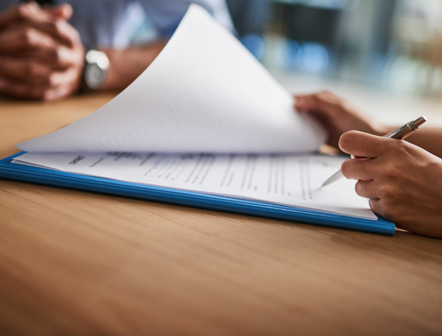 A person is writing on a piece of paper with a pen.