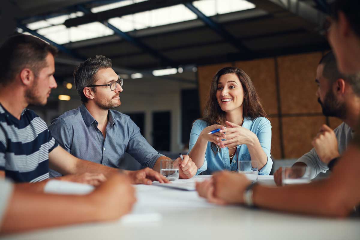 A group of people are sitting around a table having a meeting.
