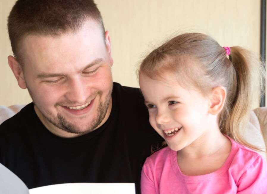 A man and a little girl are reading a book together.