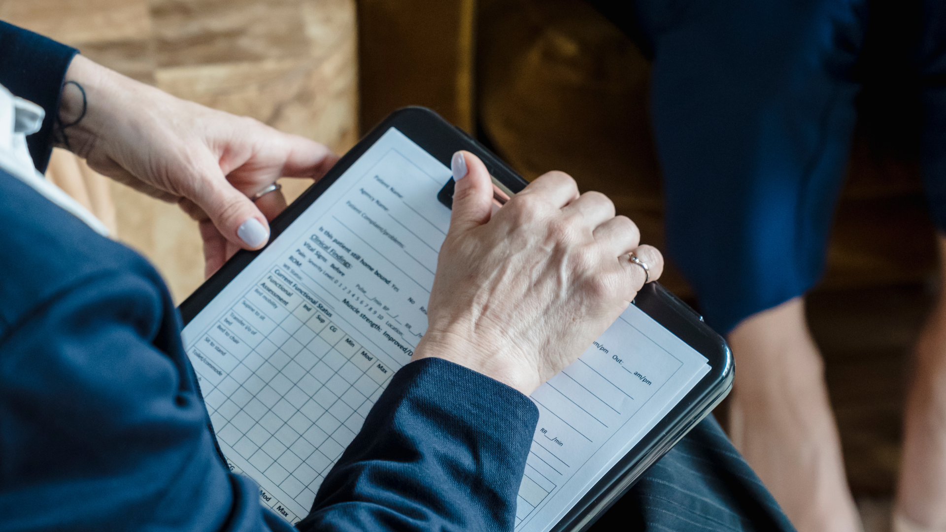 A person is holding a tablet and writing on it.