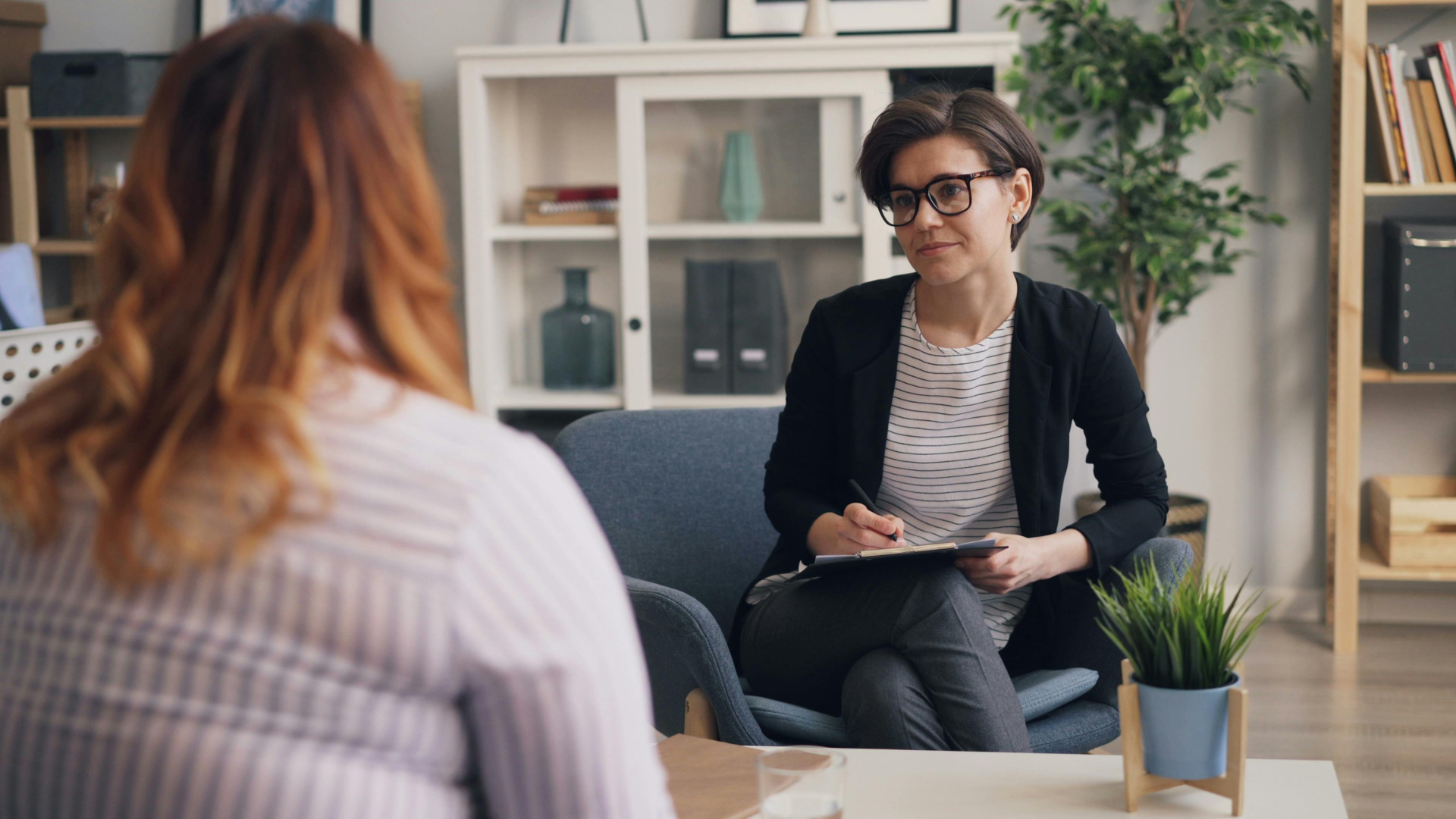 A woman is sitting at a table talking to another woman.
