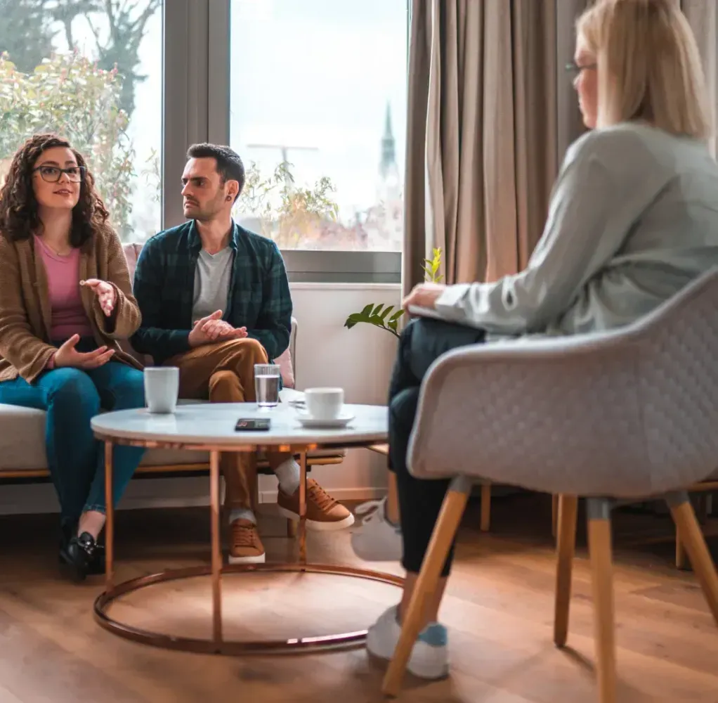 A man and a woman are sitting on a couch talking to a woman.