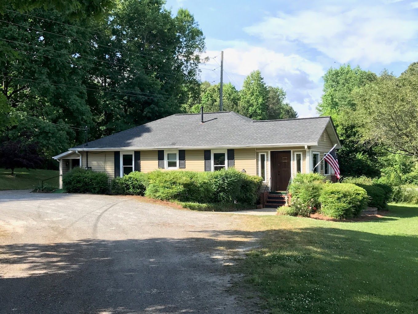 A house with a gray roof is surrounded by trees and bushes