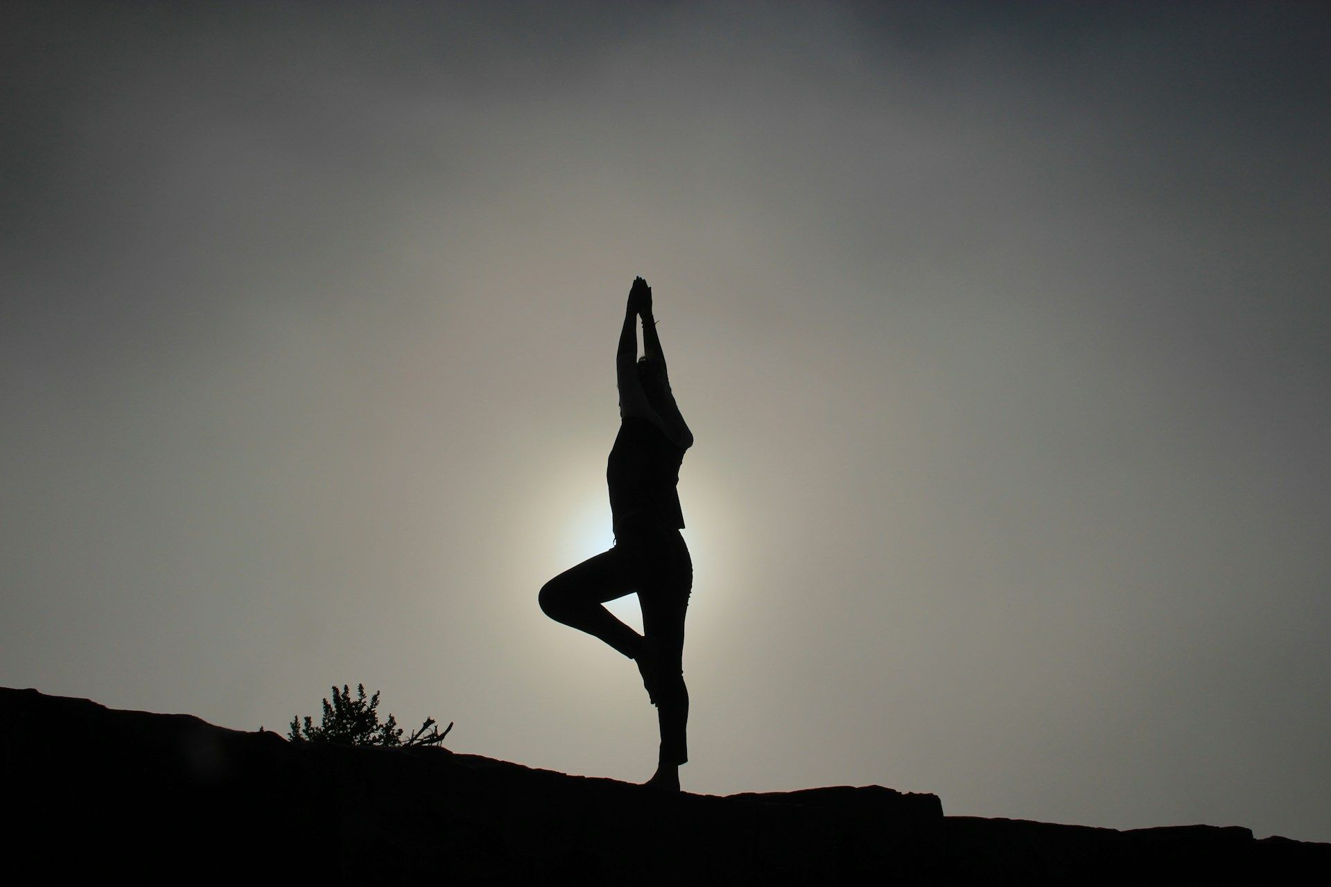 A silhouette of a person doing yoga in front of the sun