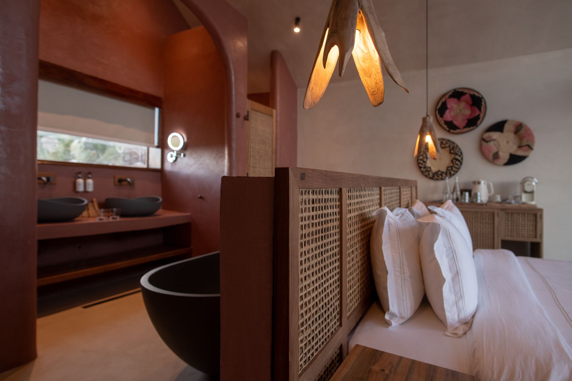 Pink-walled bathroom with woven panel doors, arched entry to sink area, and a dark bathtub.