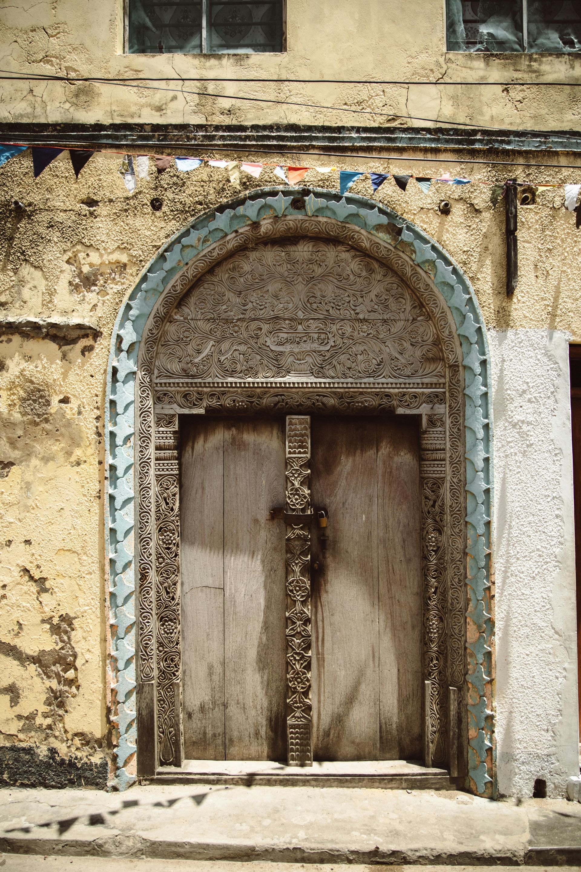 A wooden door with a blue arch on the side of a building.