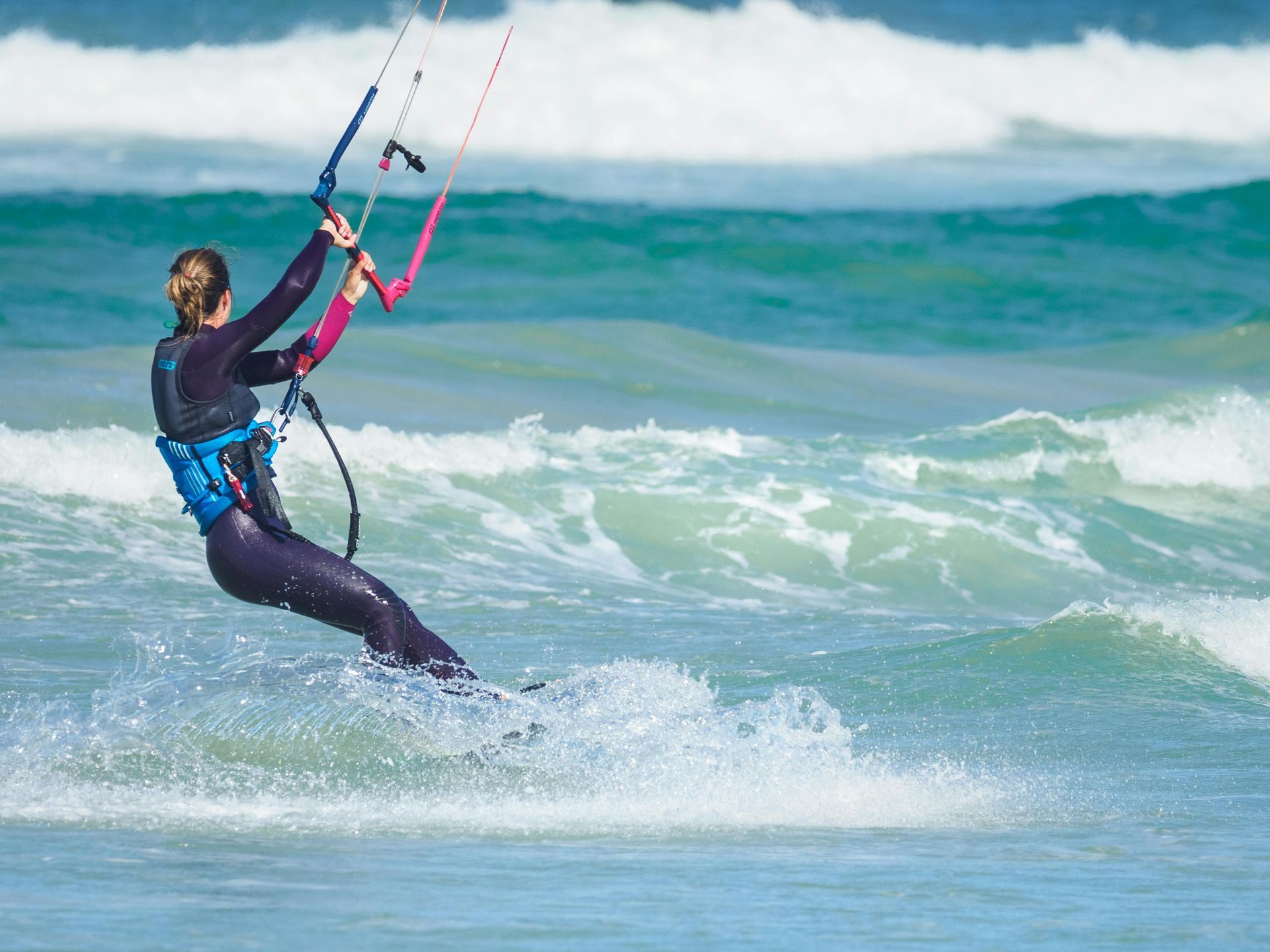 A woman is flying a kite in the ocean.
