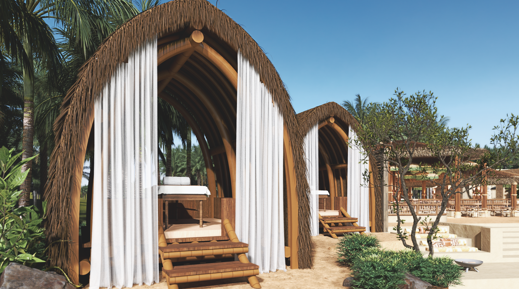 Beachside bamboo cabanas with thatched roofs, white curtains, and a massage table. Sunny day.