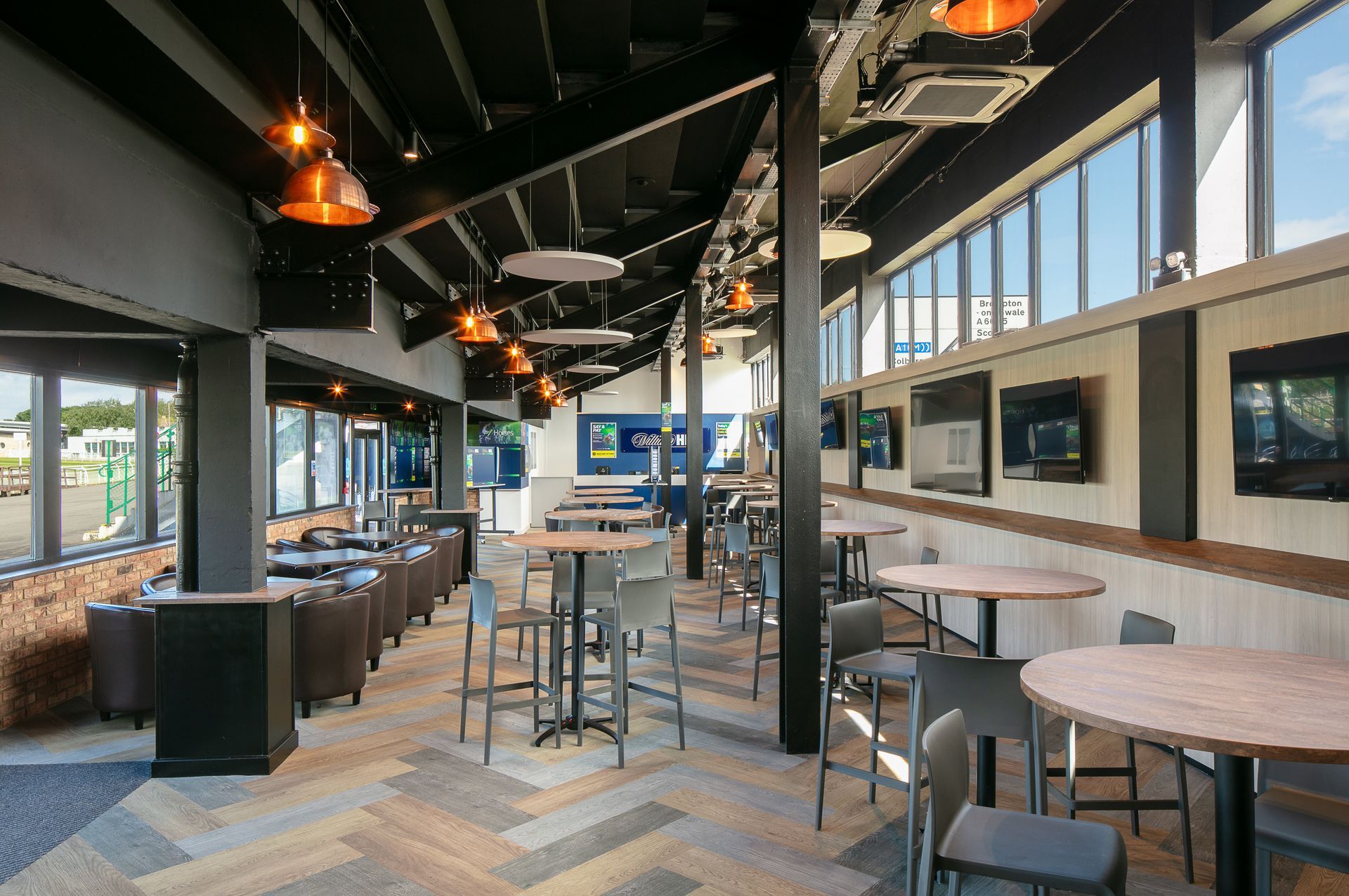 A restaurant with tables and chairs and a lot of windows.