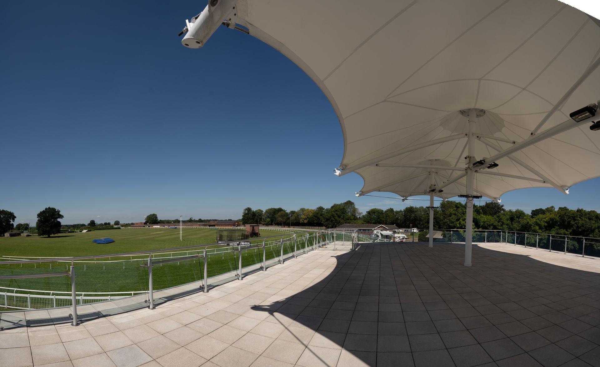 A large white umbrella is sitting on a patio overlooking a field