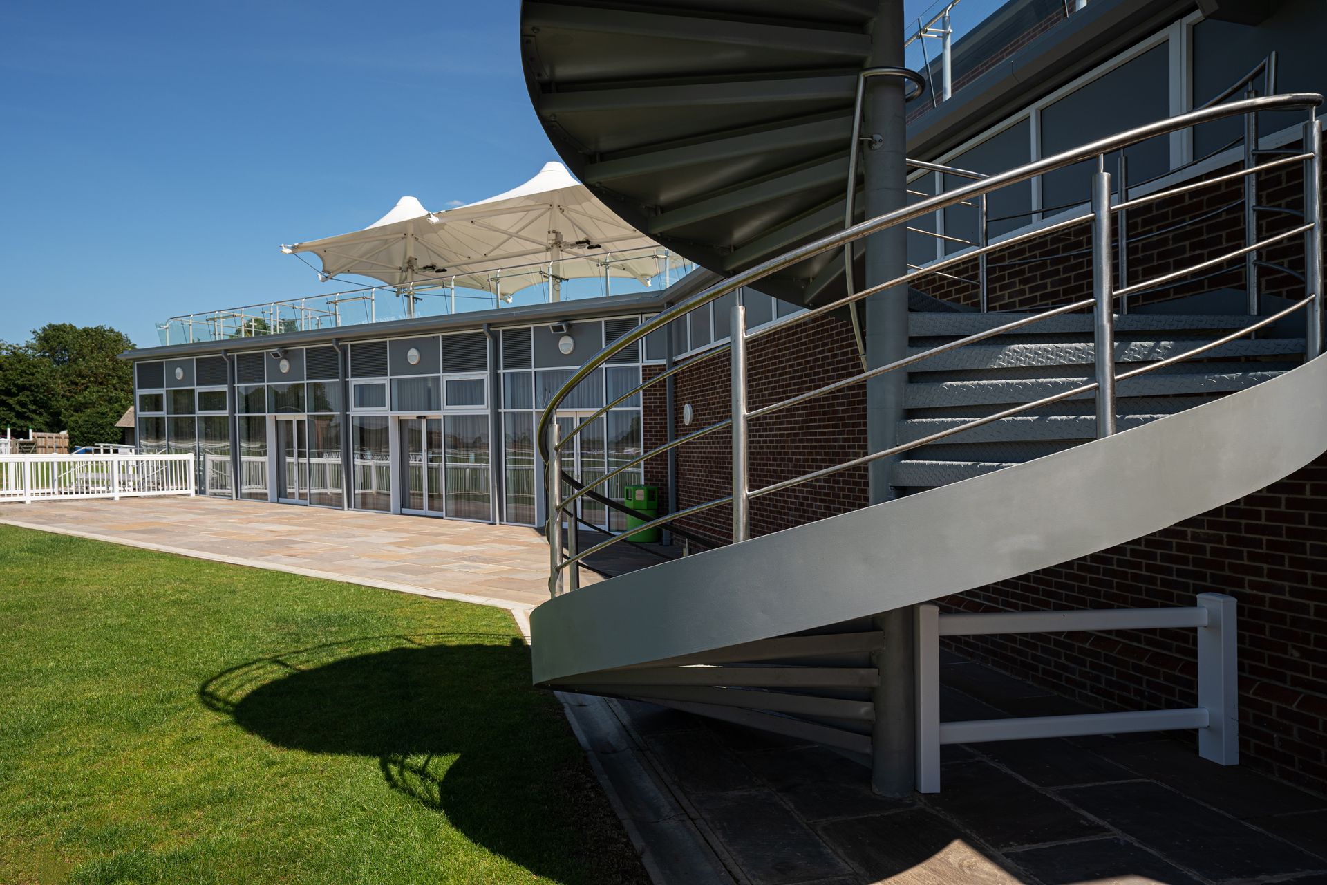 A spiral staircase leading up to a balcony with umbrellas in the background.