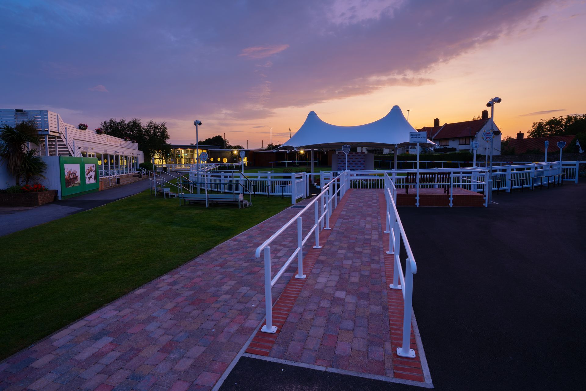A brick walkway leading to a white tent at sunset
