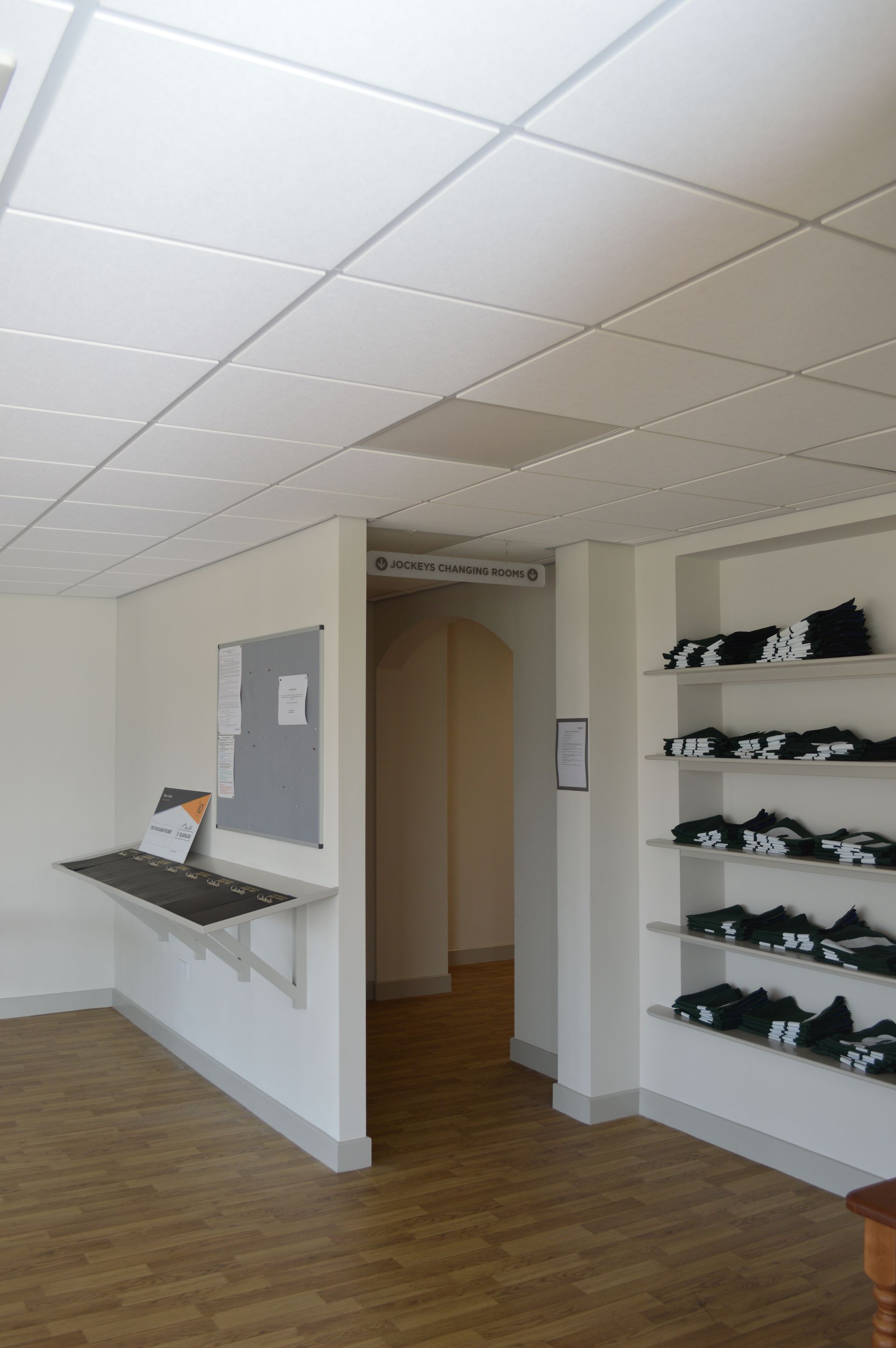 A room with a bulletin board and shelves with shirts on them