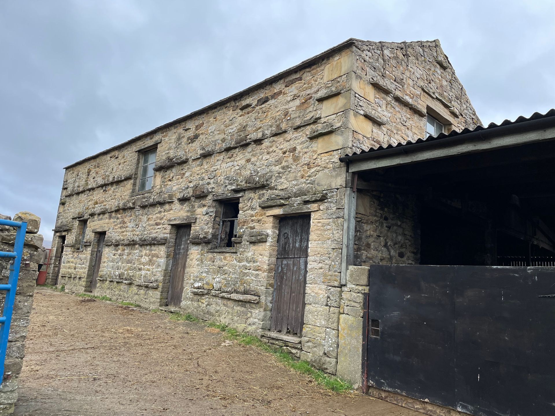 A large stone building with a blue ladder in front of it.