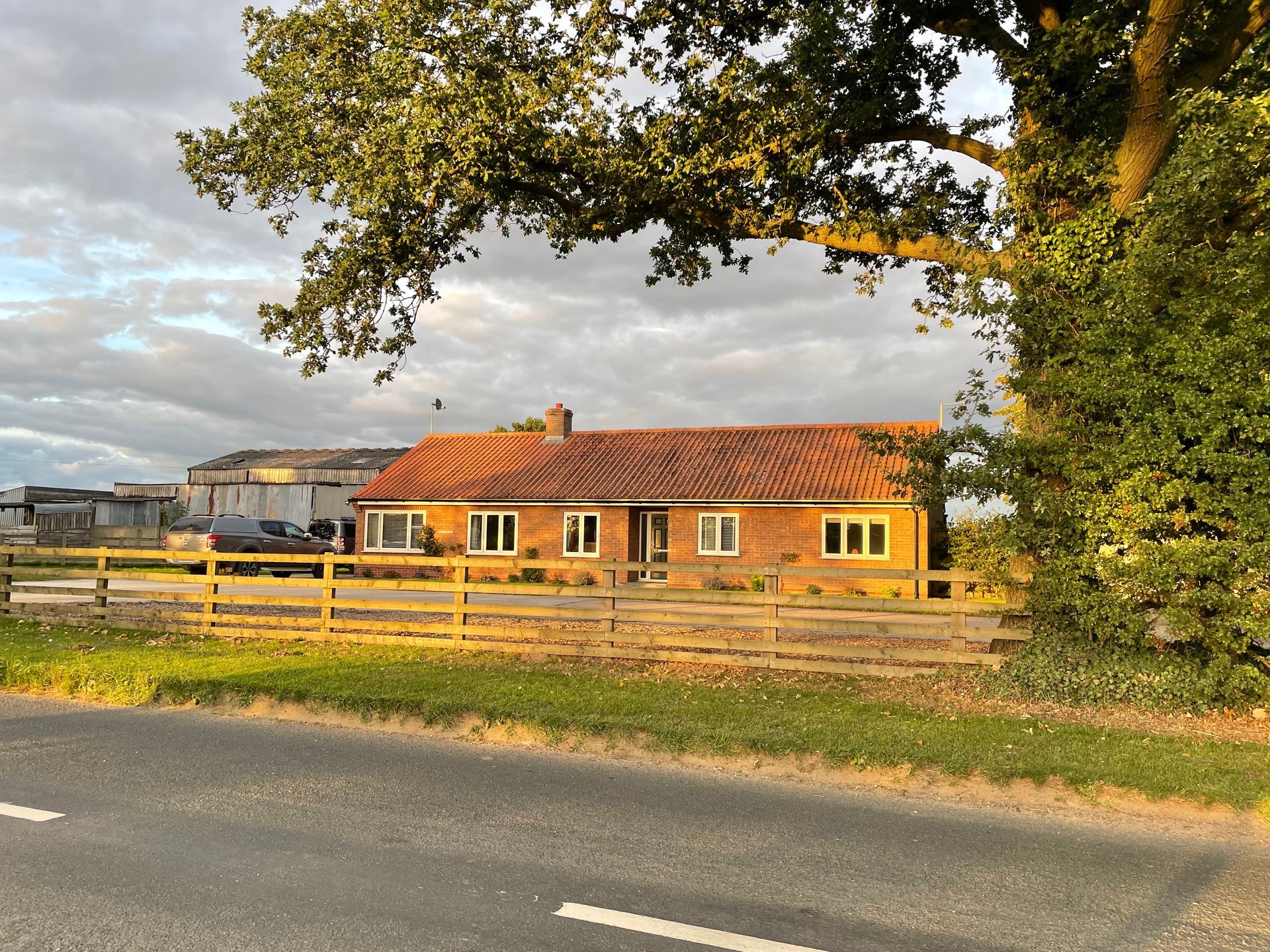 A house with a wooden fence and a tree in front of it