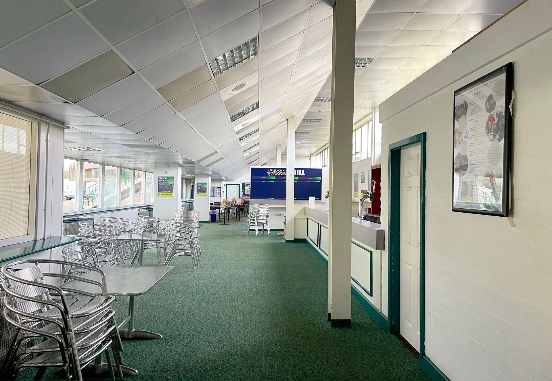 A long hallway in a building with tables and chairs
