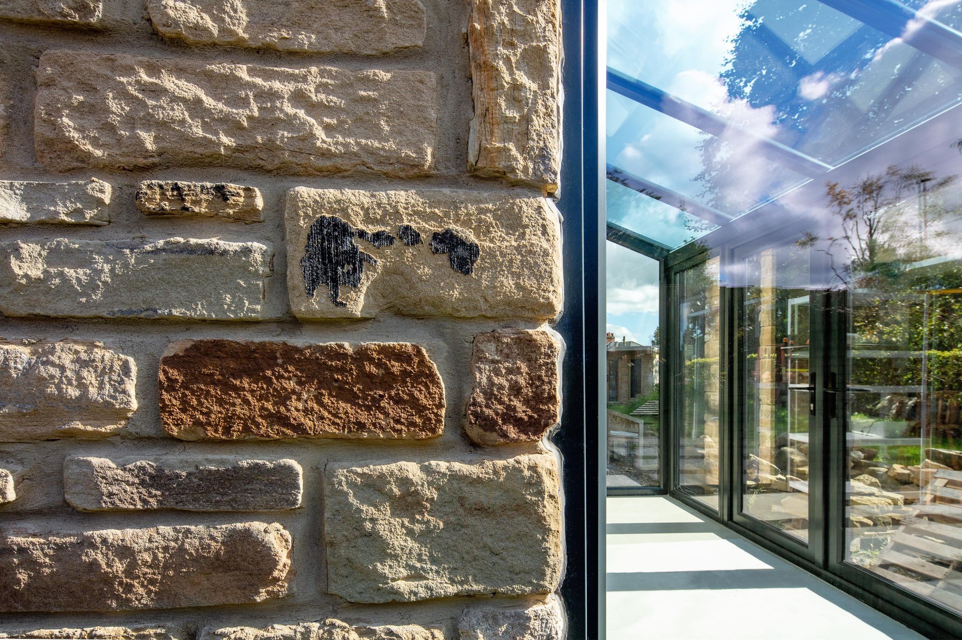 A close up of a brick wall next to a glass wall.