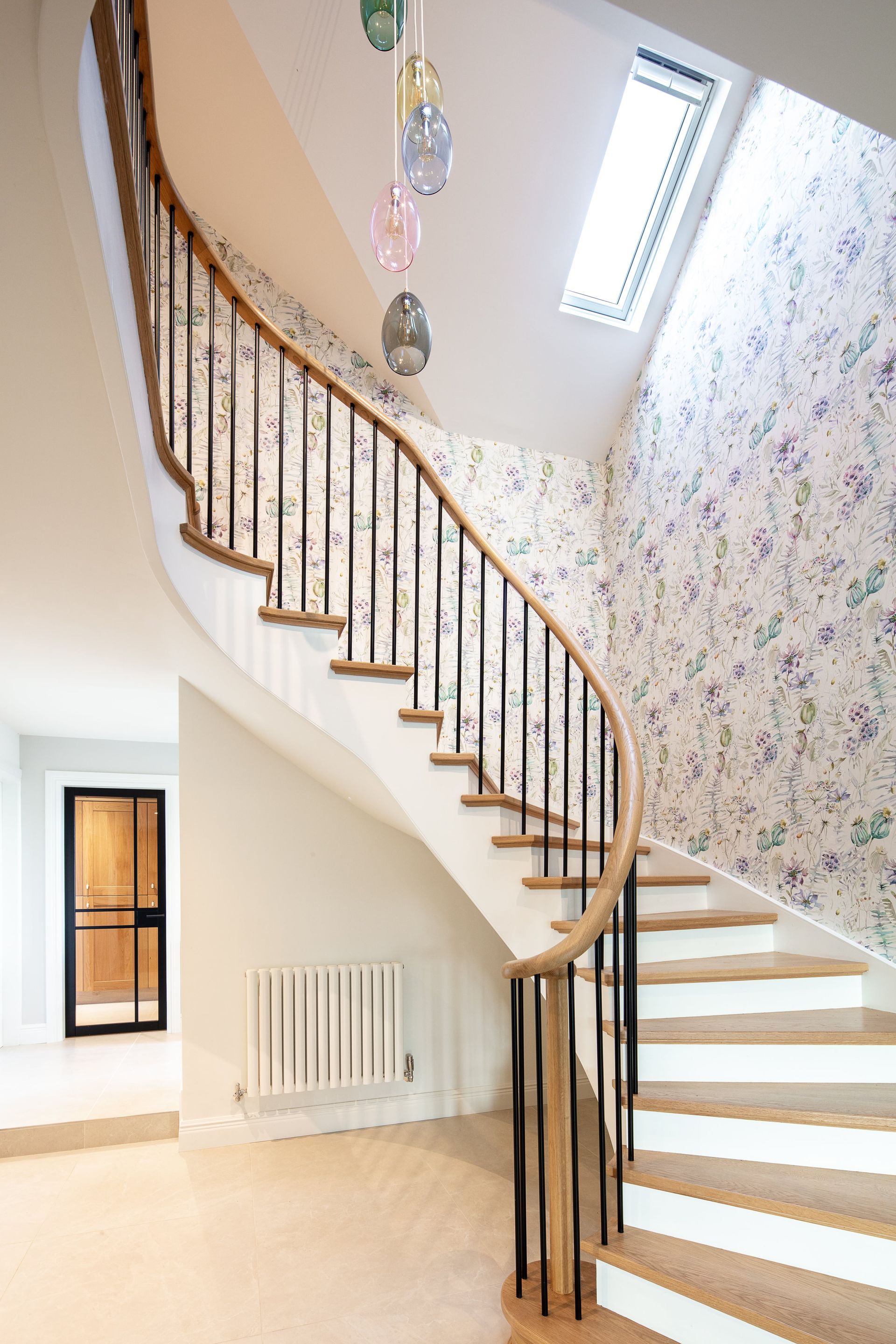 A spiral staircase in a house with a floral wallpaper on the wall.