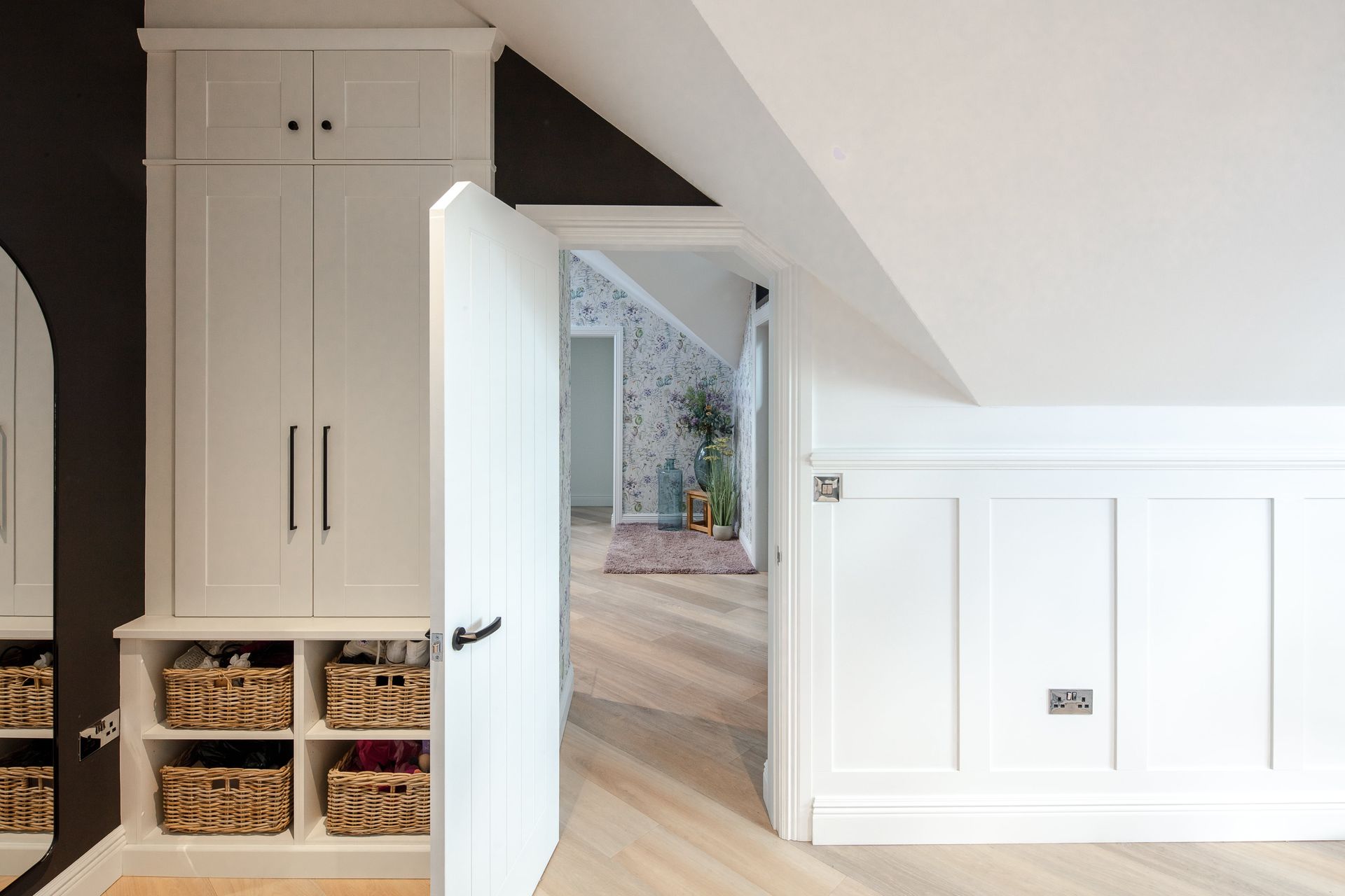 A room with white cabinets and wicker baskets in it.