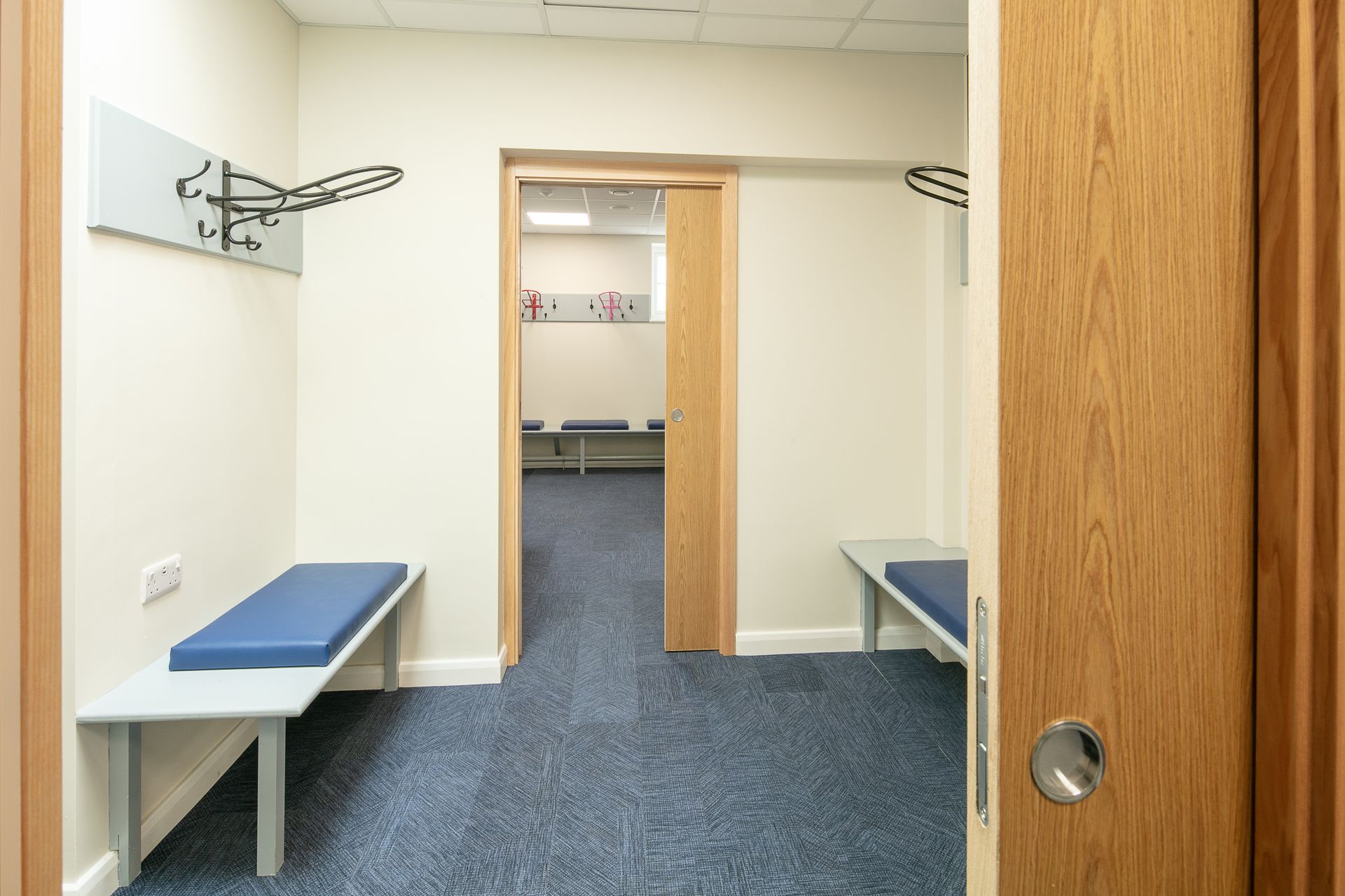 A hallway with a bench and a door leading to a room.
