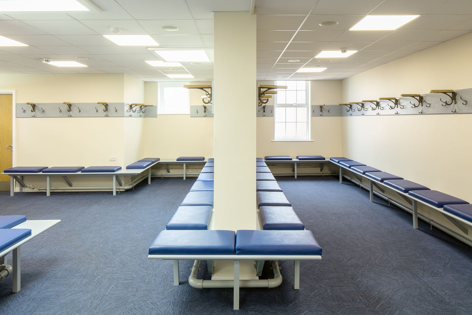 A locker room with blue benches and white walls