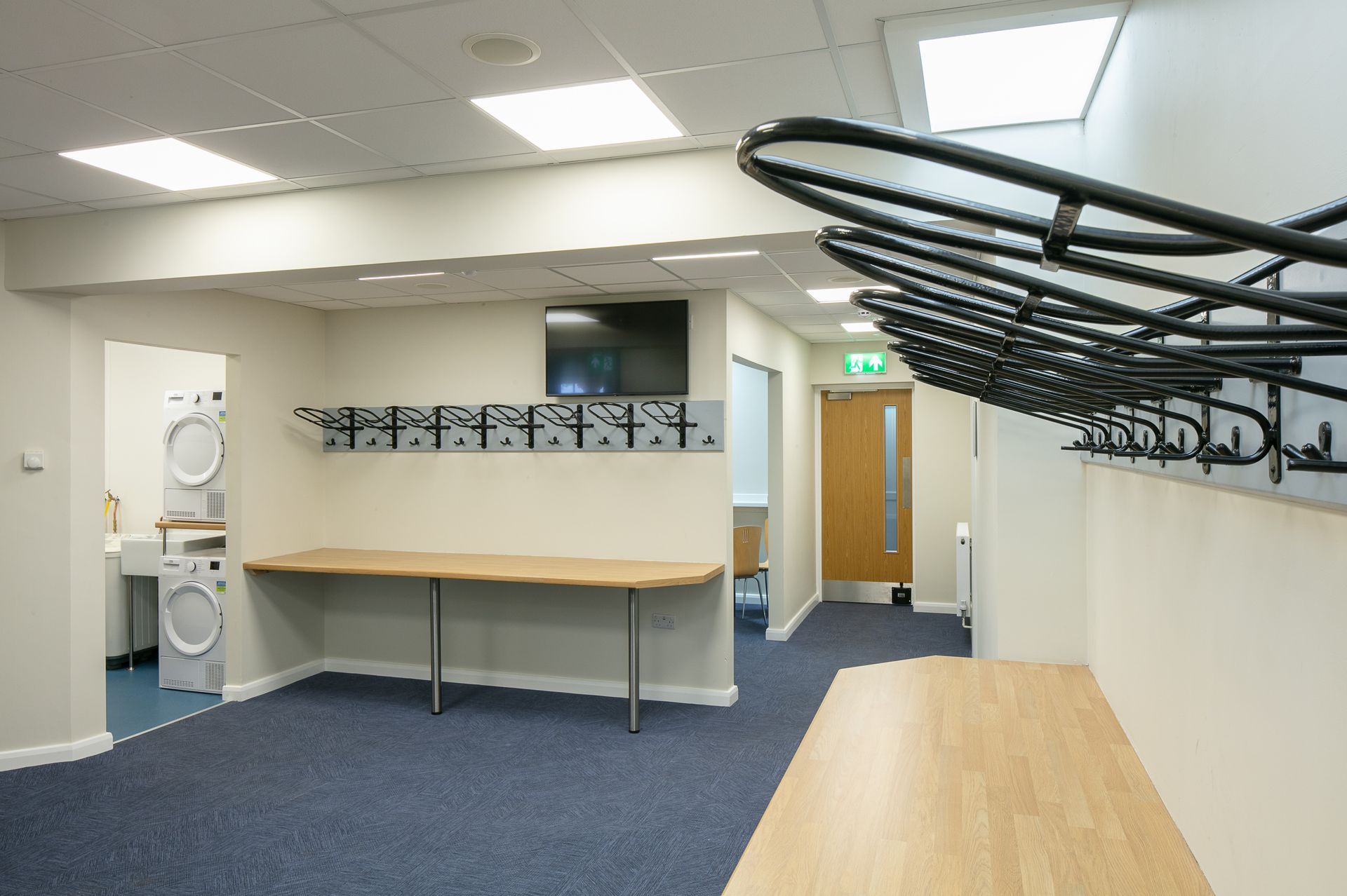 A room with a wooden table and a row of clothes racks on the wall.
