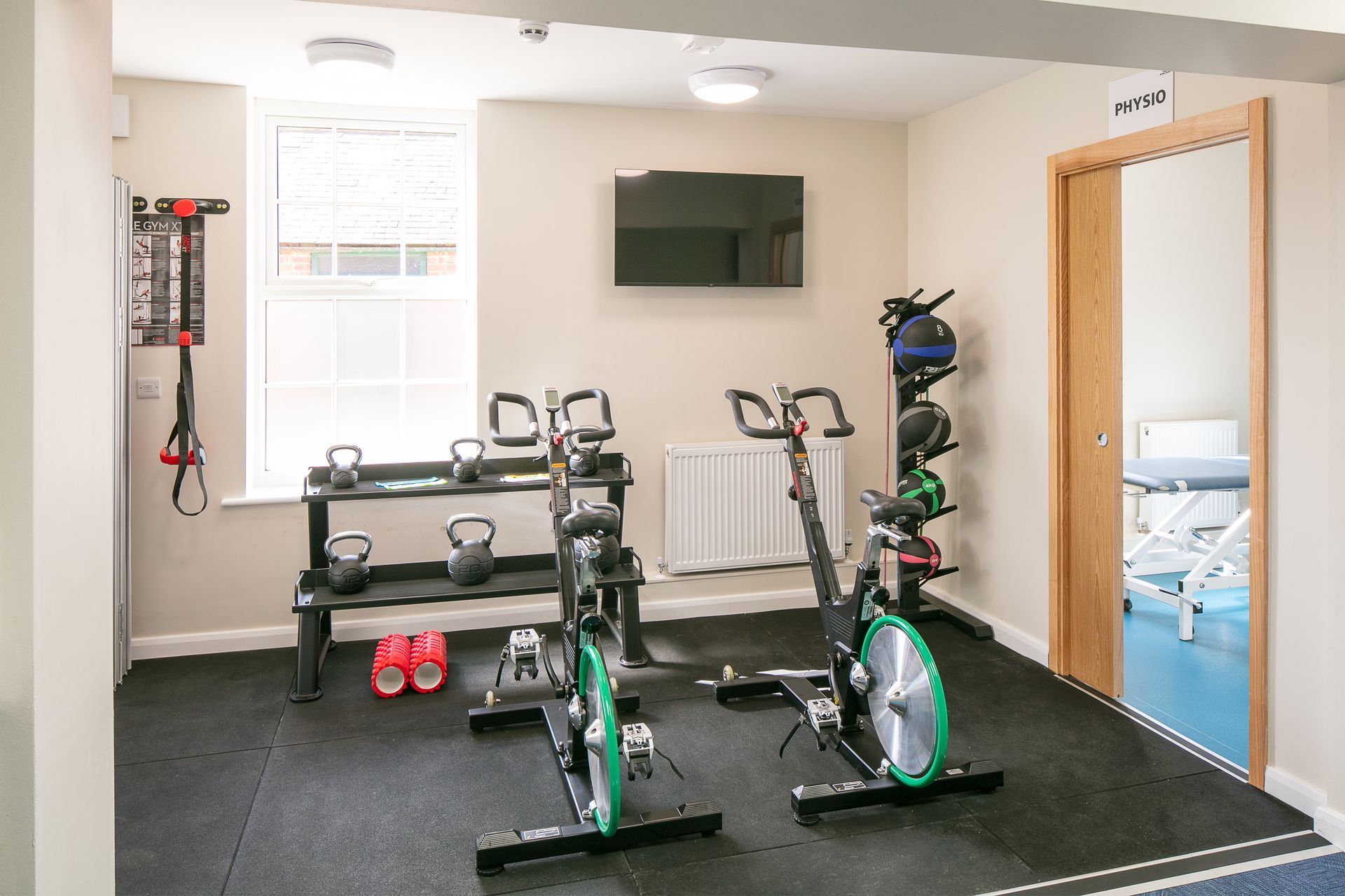 A gym with two exercise bikes and a television on the wall.