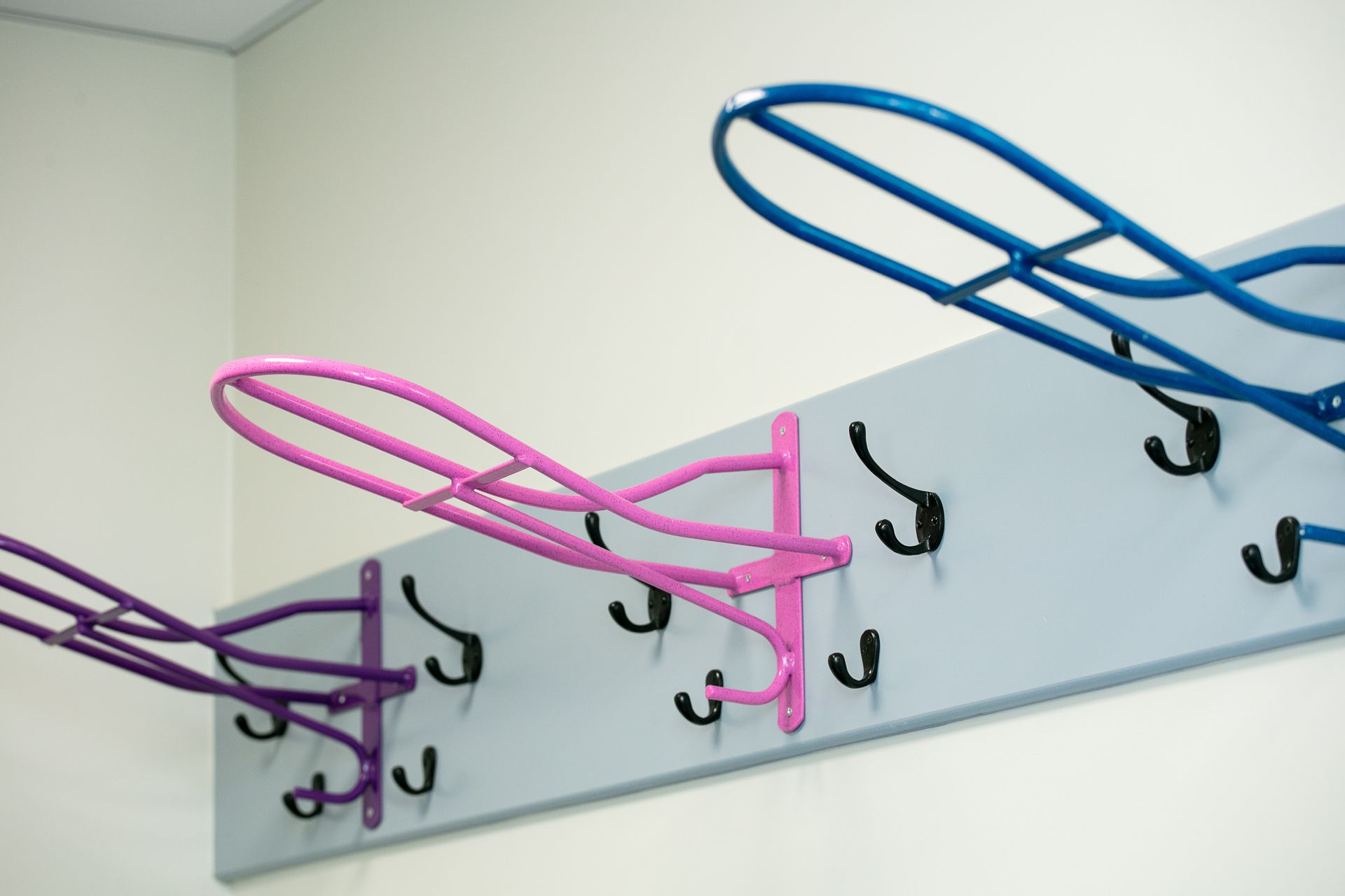 A row of pink and blue hooks on a wall