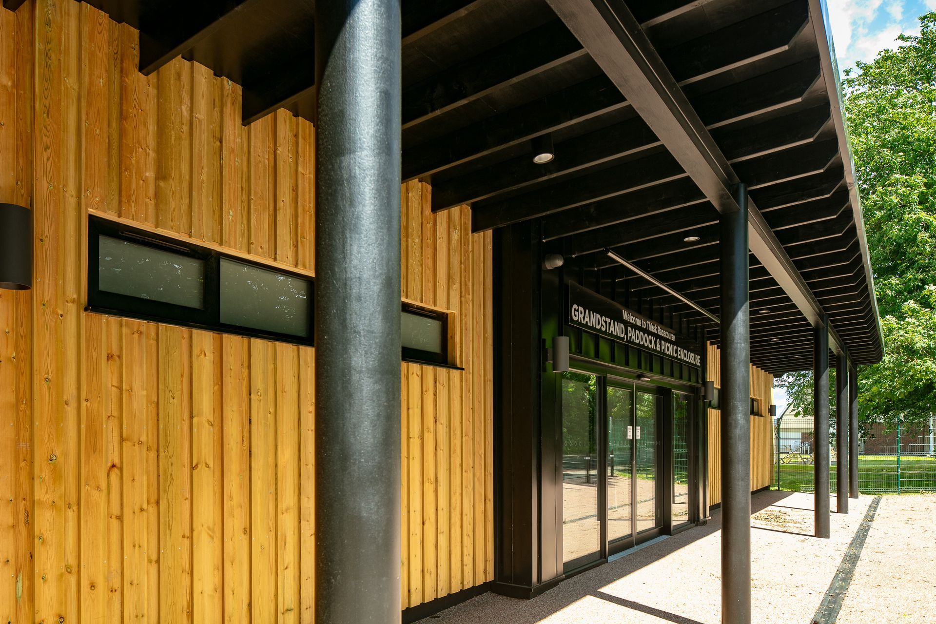 A wooden building with a black roof and a covered walkway.