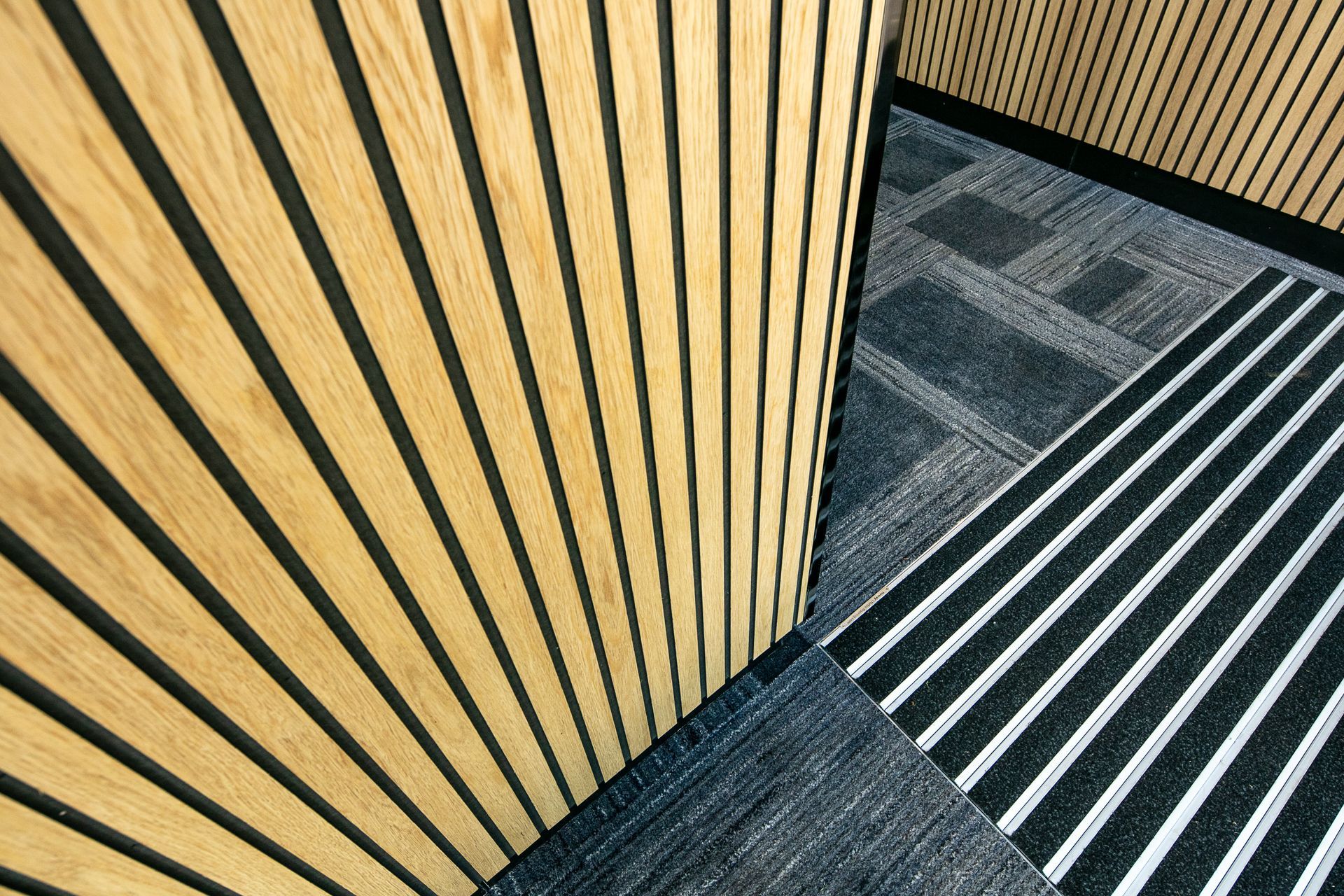 A staircase with a wooden wall and black and white stripes on the floor.