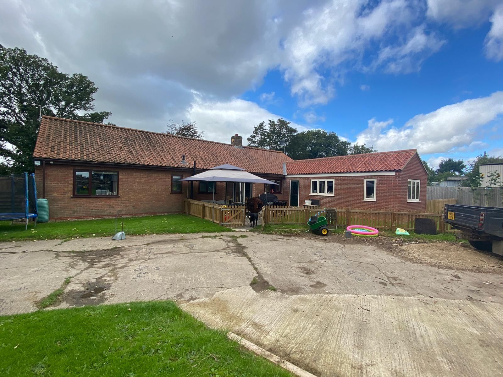 A large brick house with a red tiled roof is sitting on top of a lush green field.