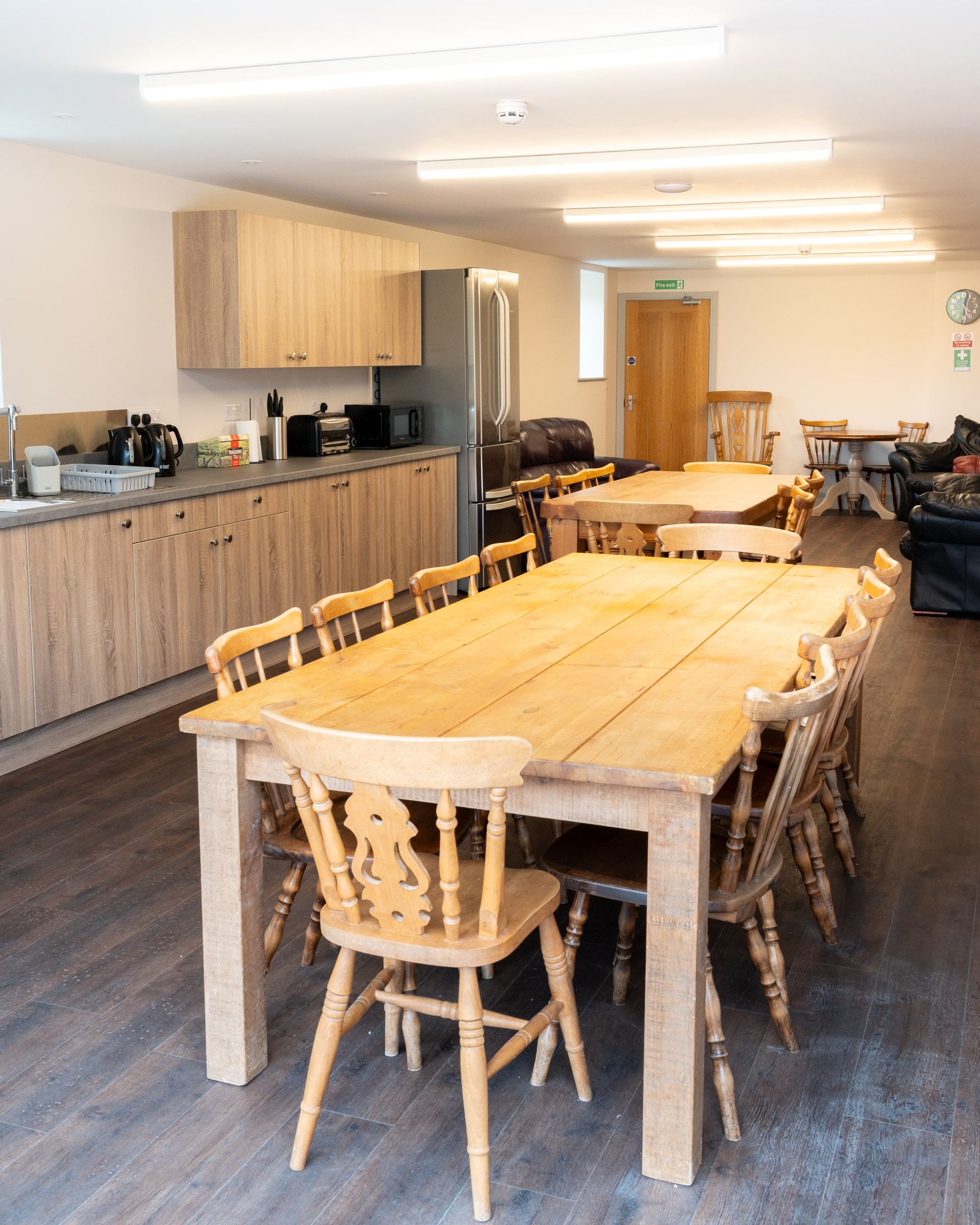 There is a long wooden table and chairs in the middle of the room.