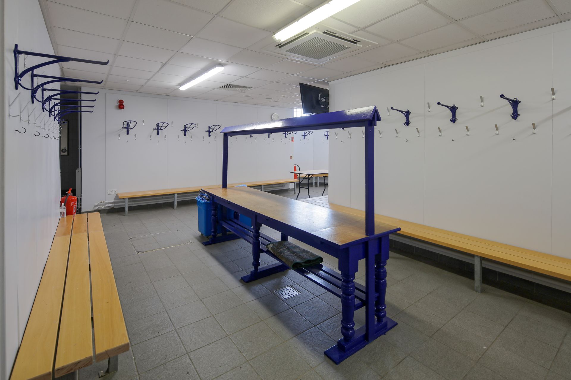 A locker room with benches and a blue table
