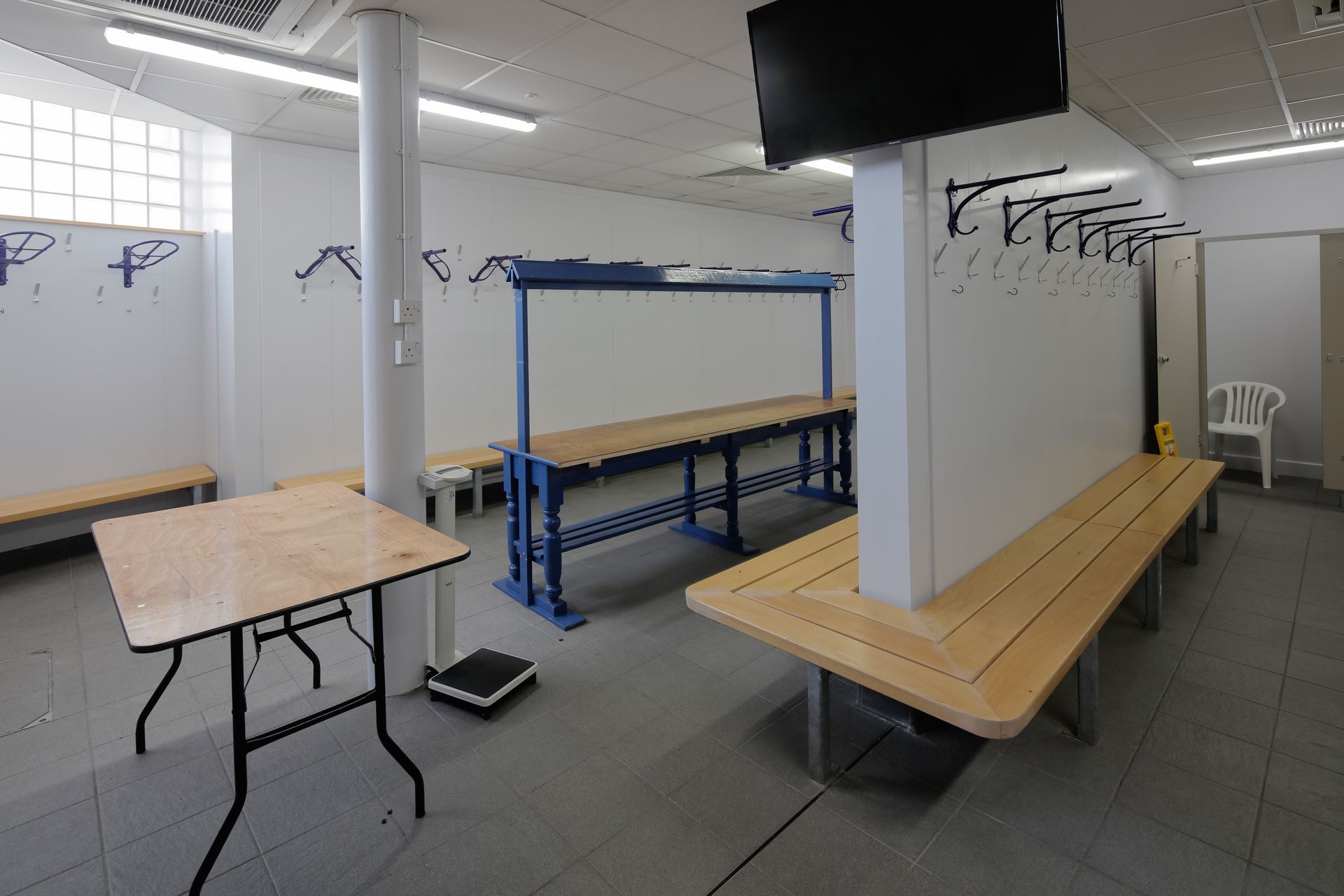 A locker room with tables and benches and a flat screen tv