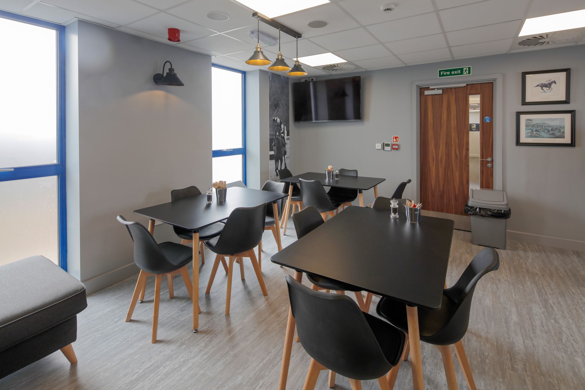 A room with tables and chairs and a television on the wall.
