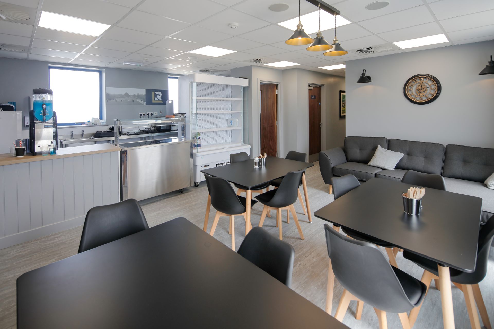 A room with tables and chairs and a clock on the wall.