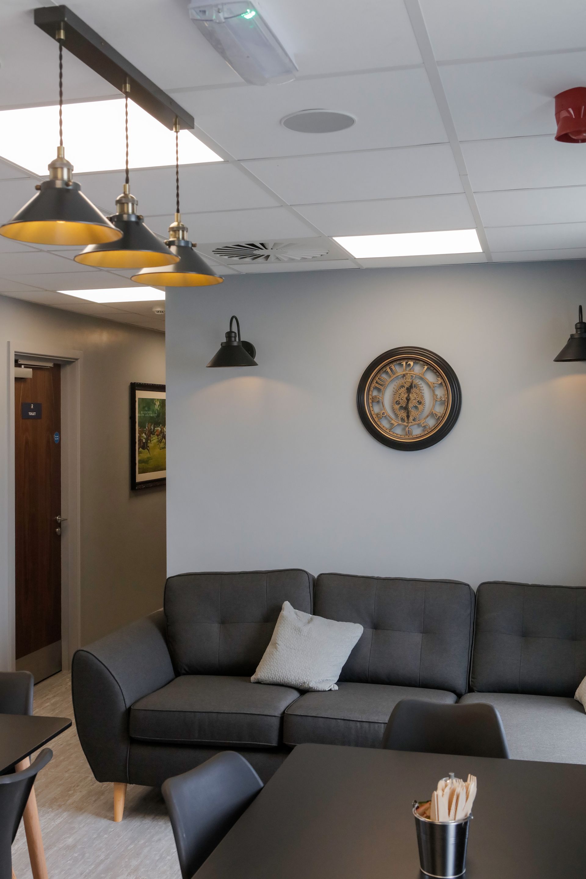 A living room with a couch , table , chairs and a clock on the wall.
