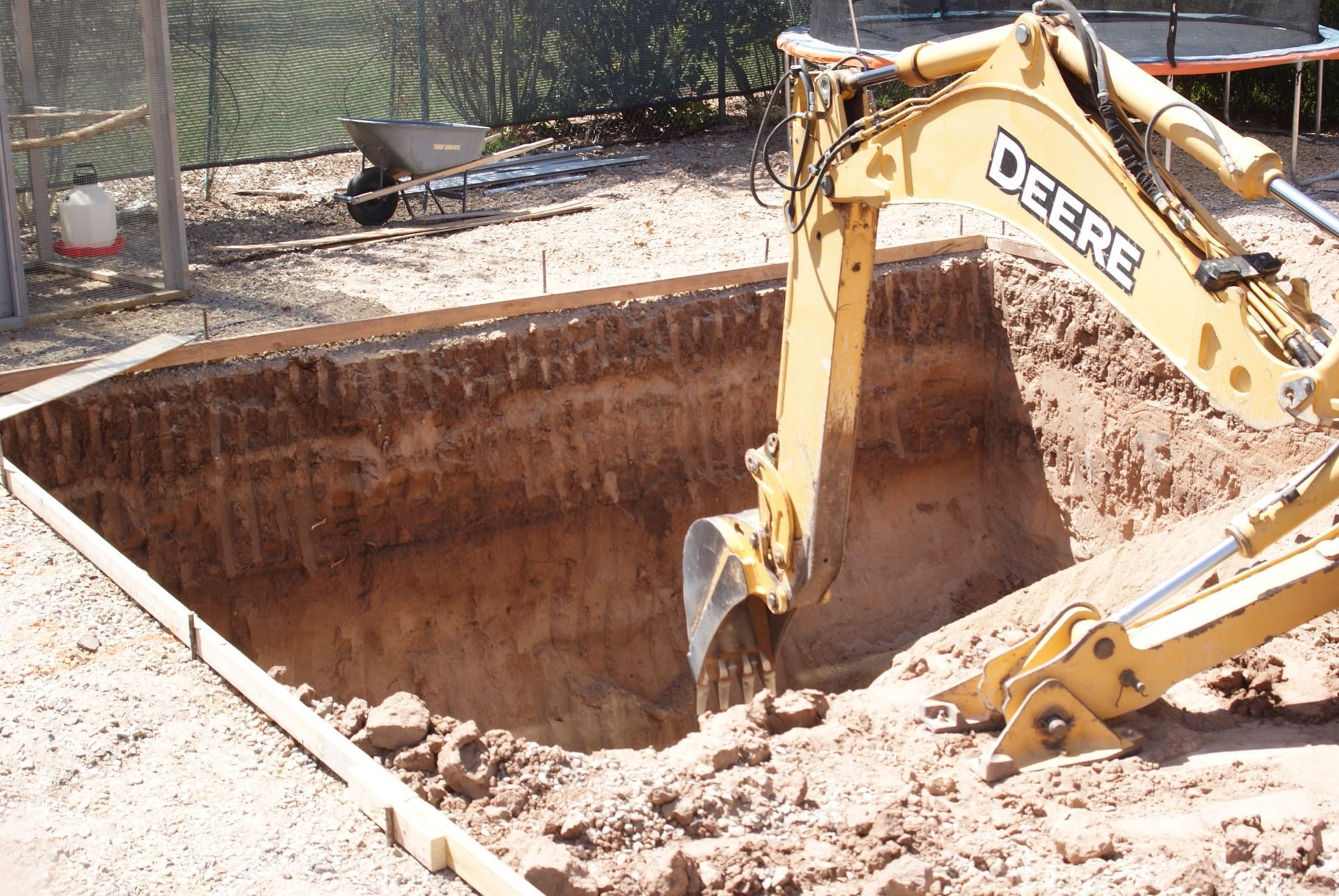A deere excavator is digging a hole in the dirt
