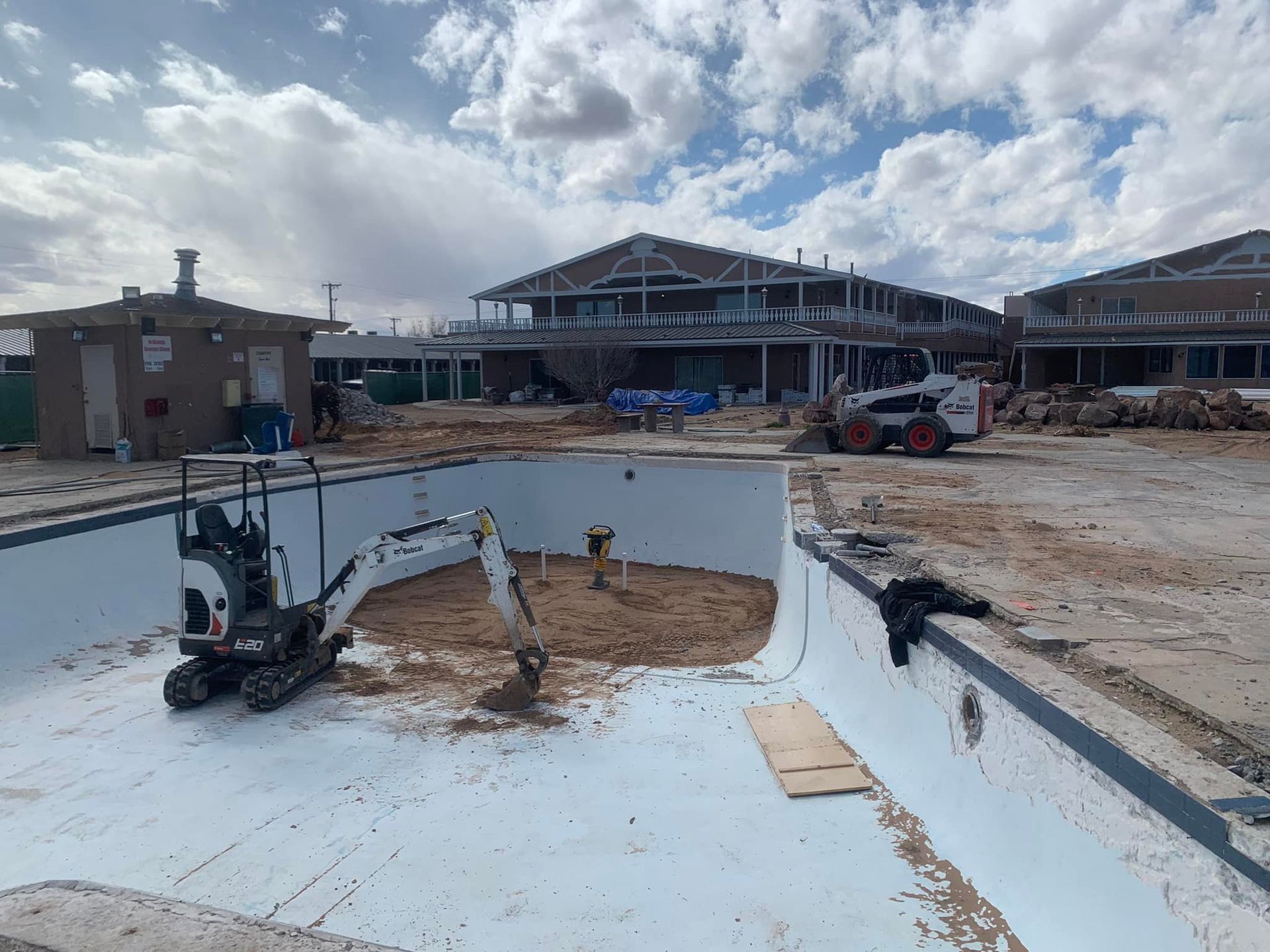 A small excavator is sitting in the middle of a swimming pool.
