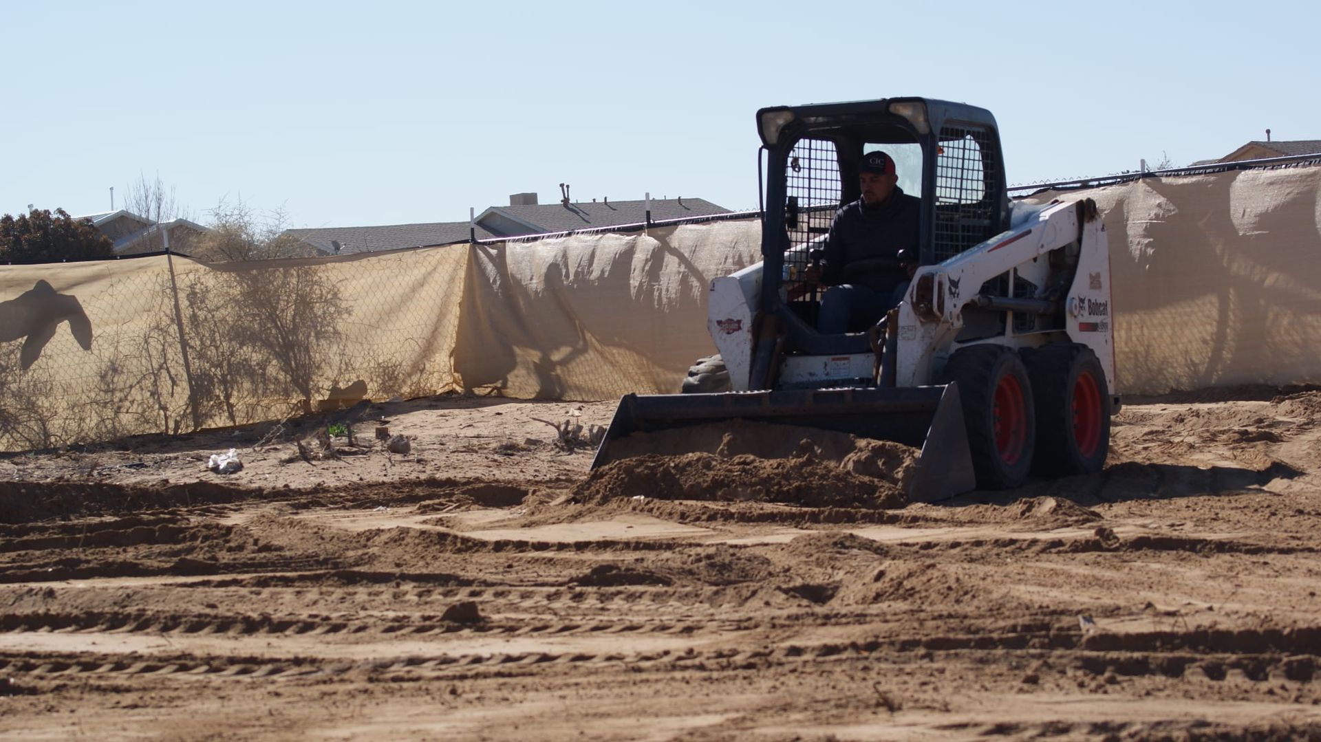 A man is driving a bulldozer in a dirt field
