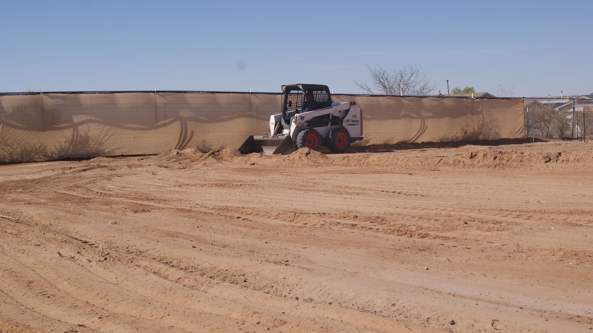 A bobcat bulldozer is moving dirt in a dirt field