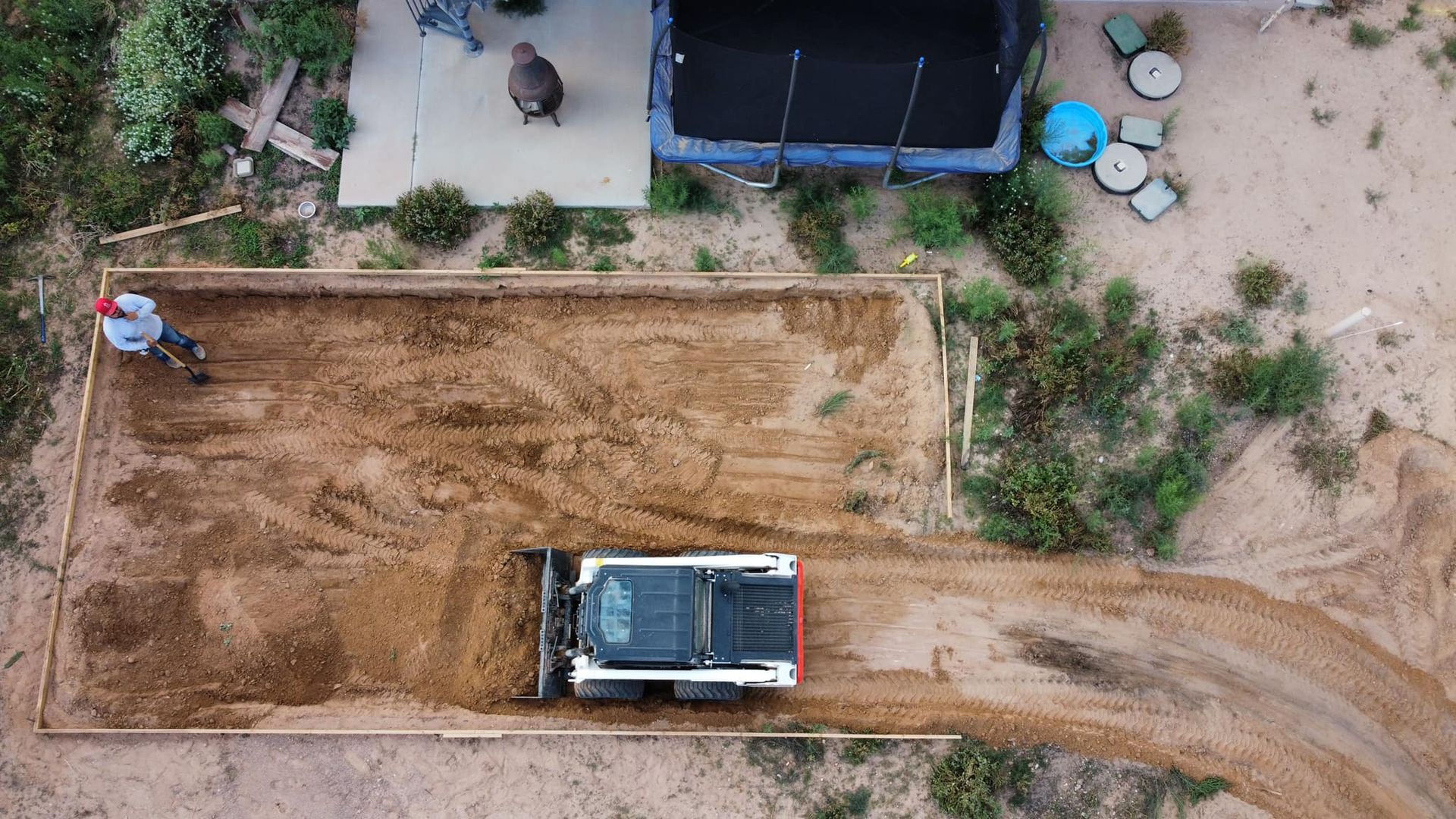 An aerial view of a bulldozer moving dirt on a dirt road.