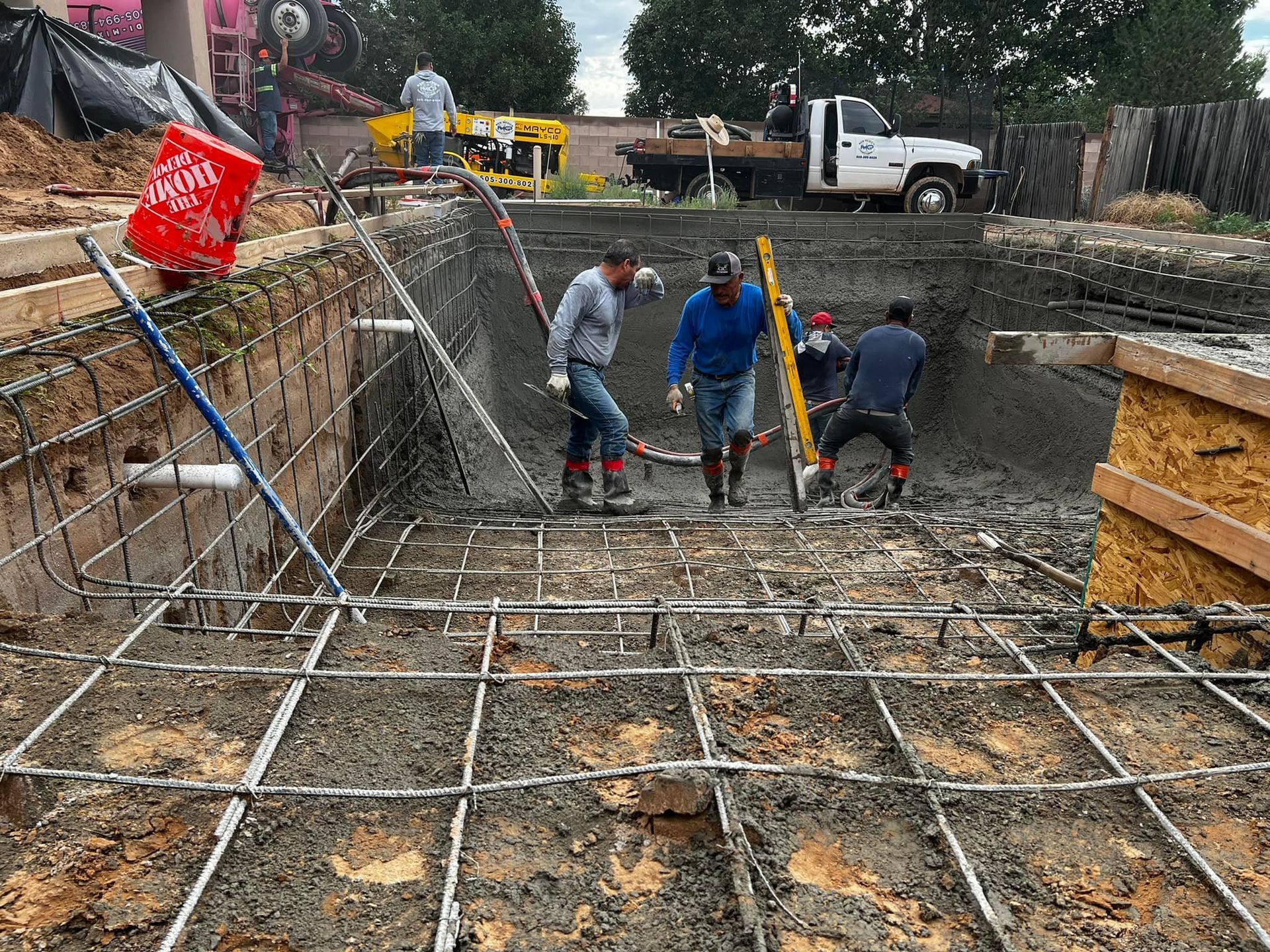 A group of construction workers are working on a swimming pool.