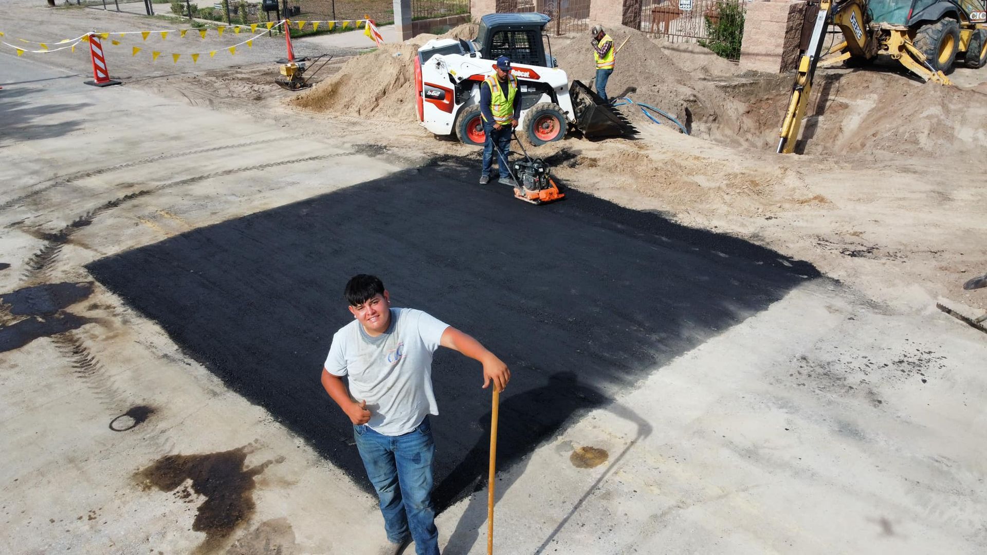 A man is standing in front of a large patch of asphalt.